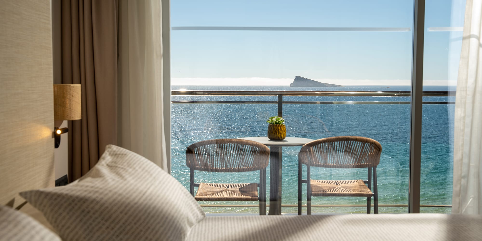 a room with a view of the ocean and a table and chairs