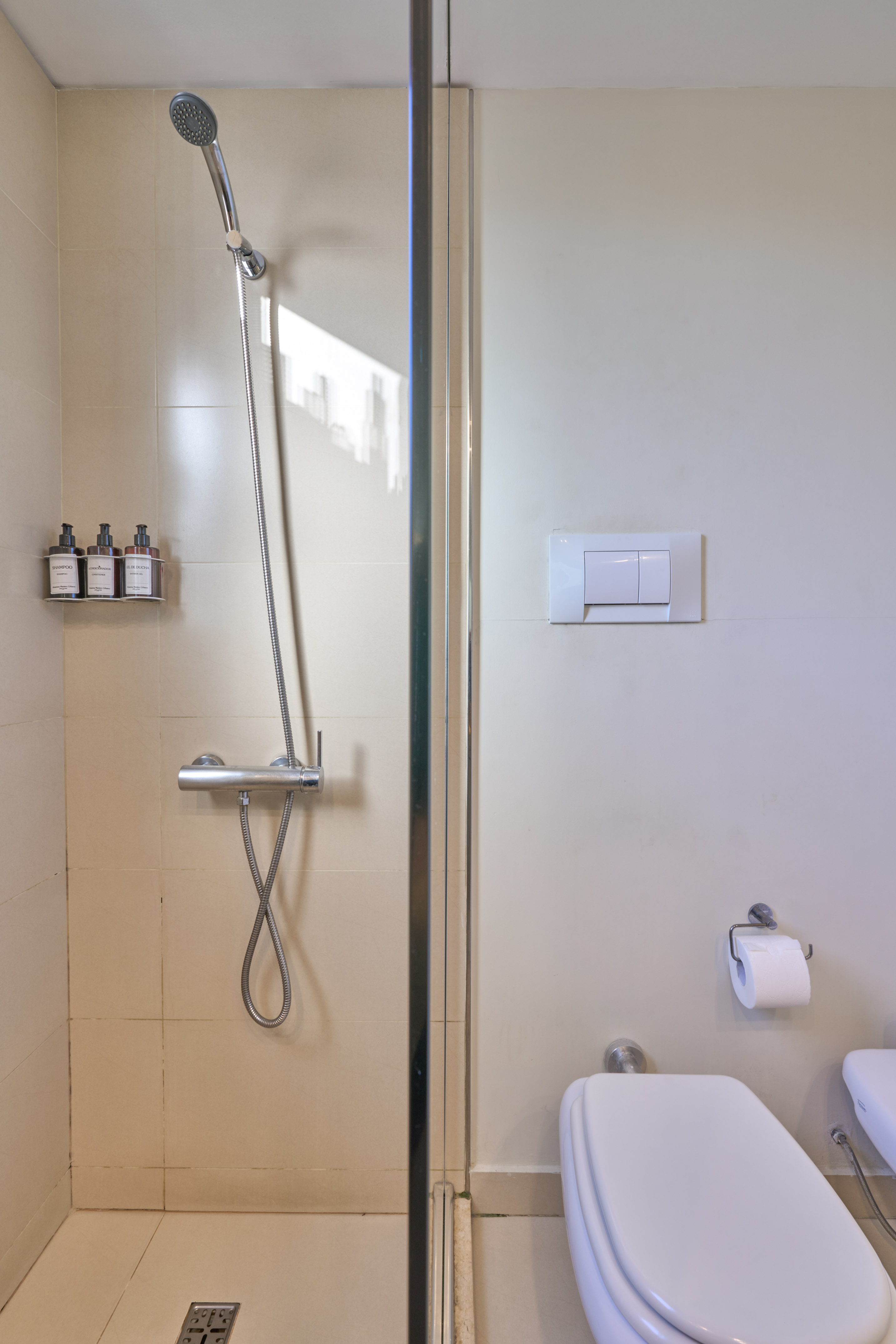 Clean tiled bathroom with glass shower and white toilet.