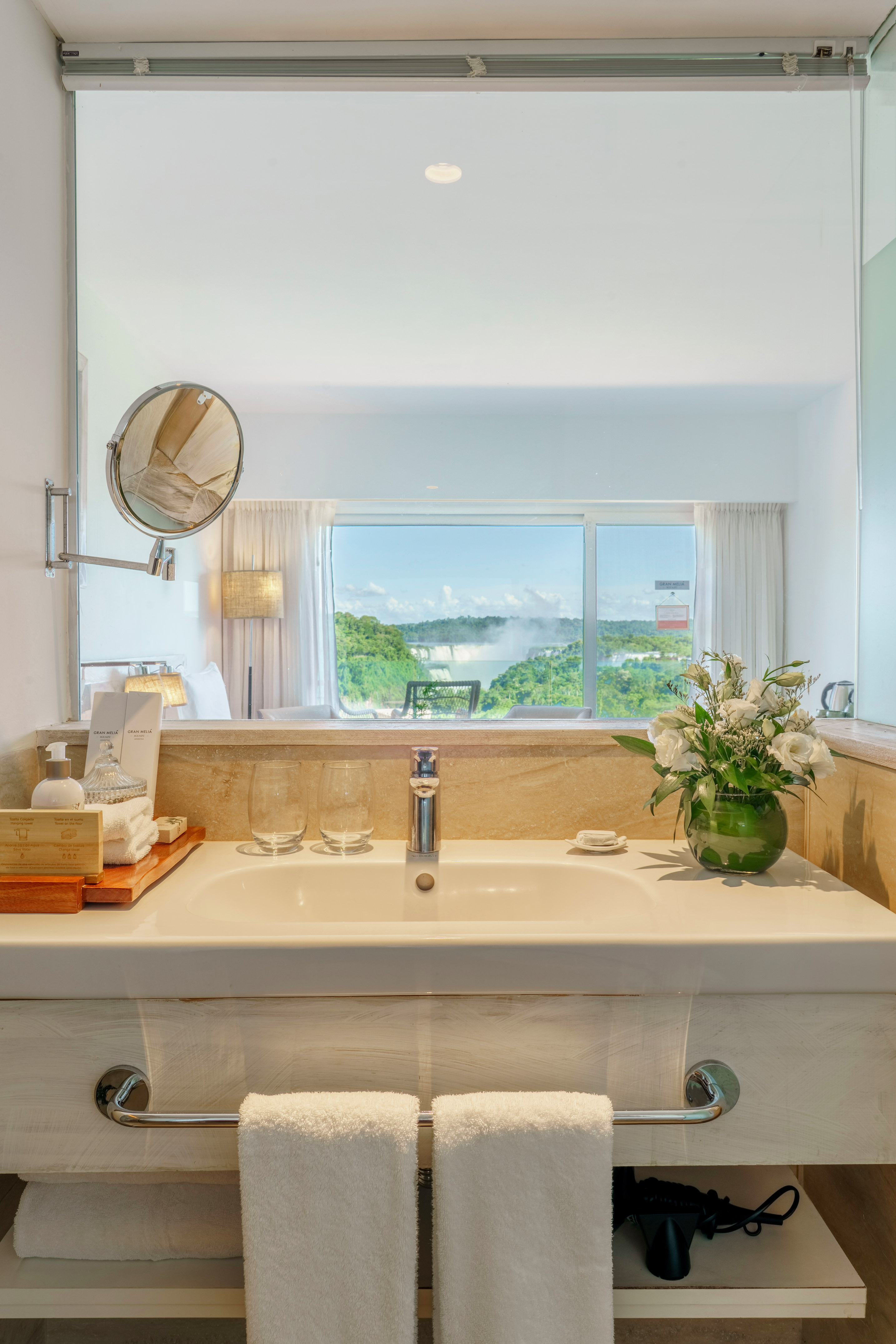 Hotel bathroom vanity with sink and mirror reflecting Iguazu Falls view.
