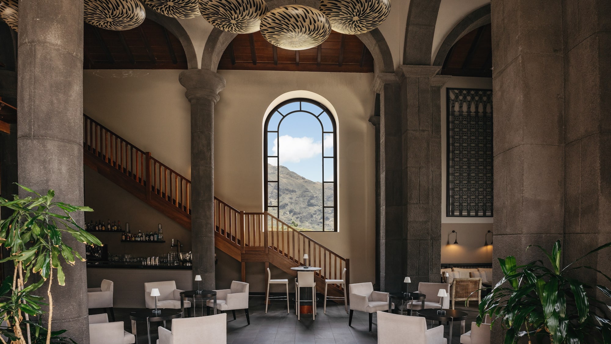 Hotel lobby with mountain view, stone pillars, arched window, and lounge seating.