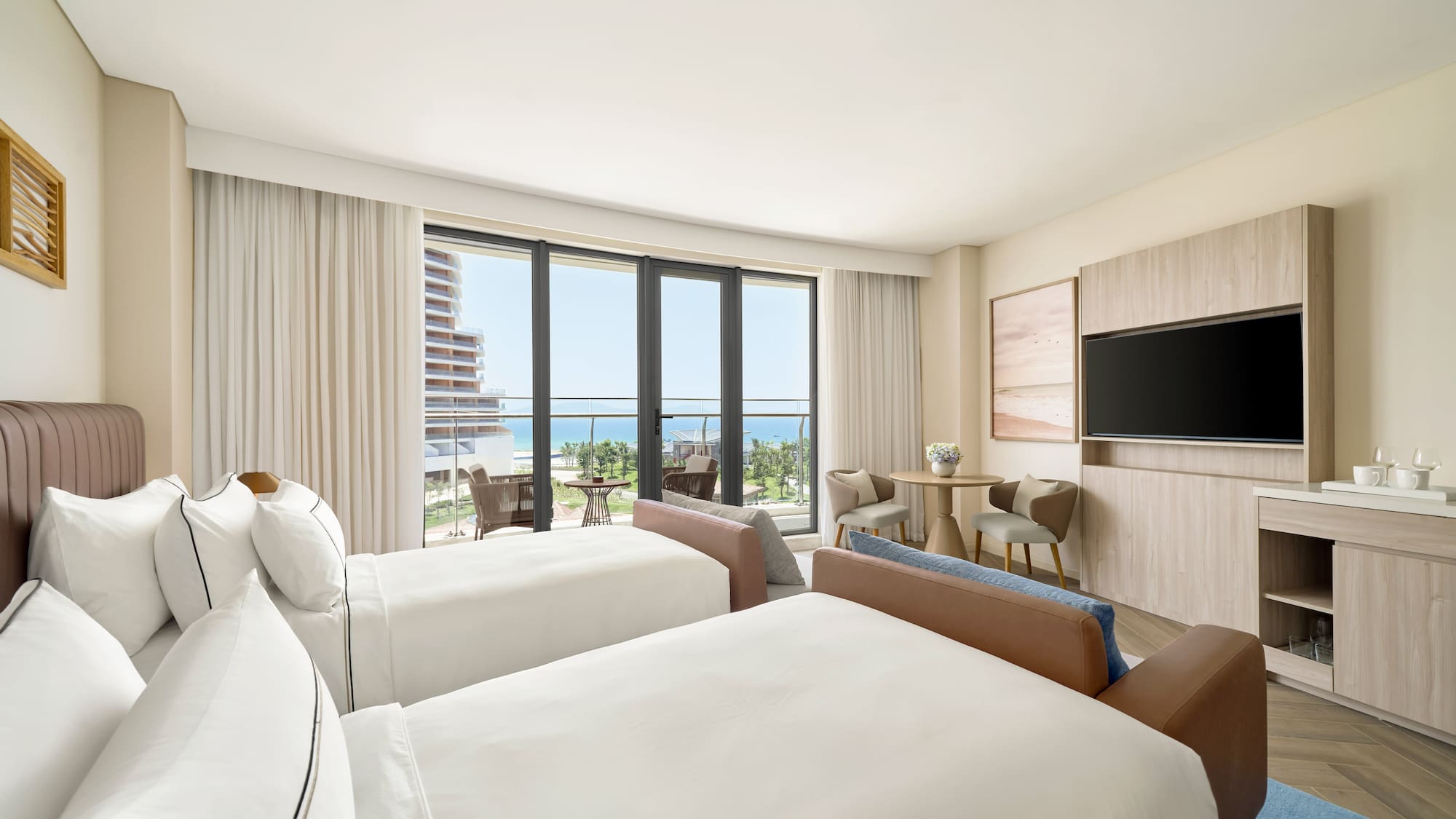 Hotel room with twin beds, ocean view balcony, and modern coastal design.