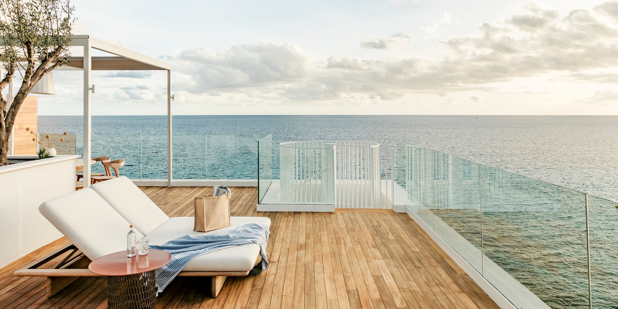 a deck with a chair and table overlooking the ocean