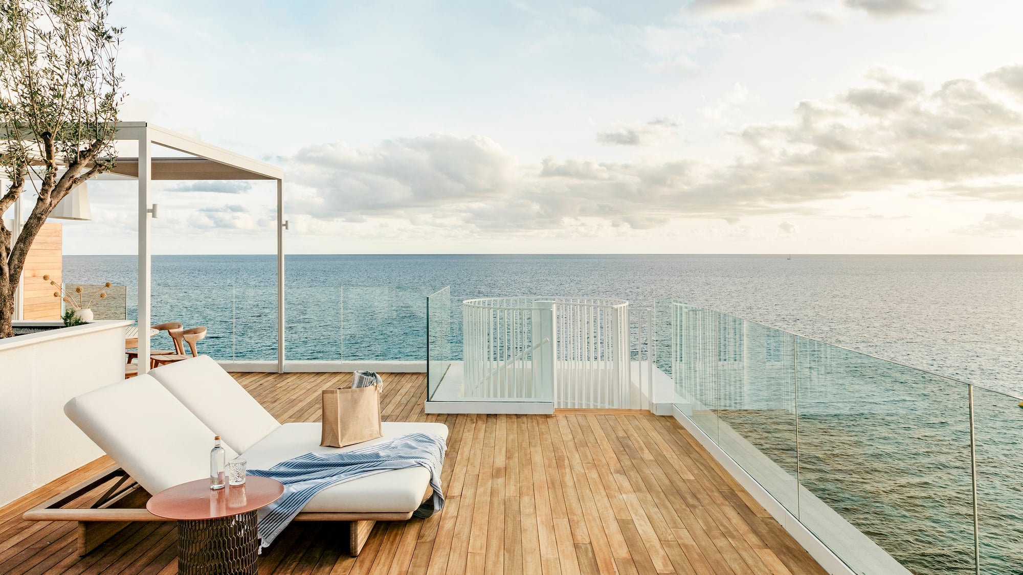 a deck with a chair and table overlooking the ocean