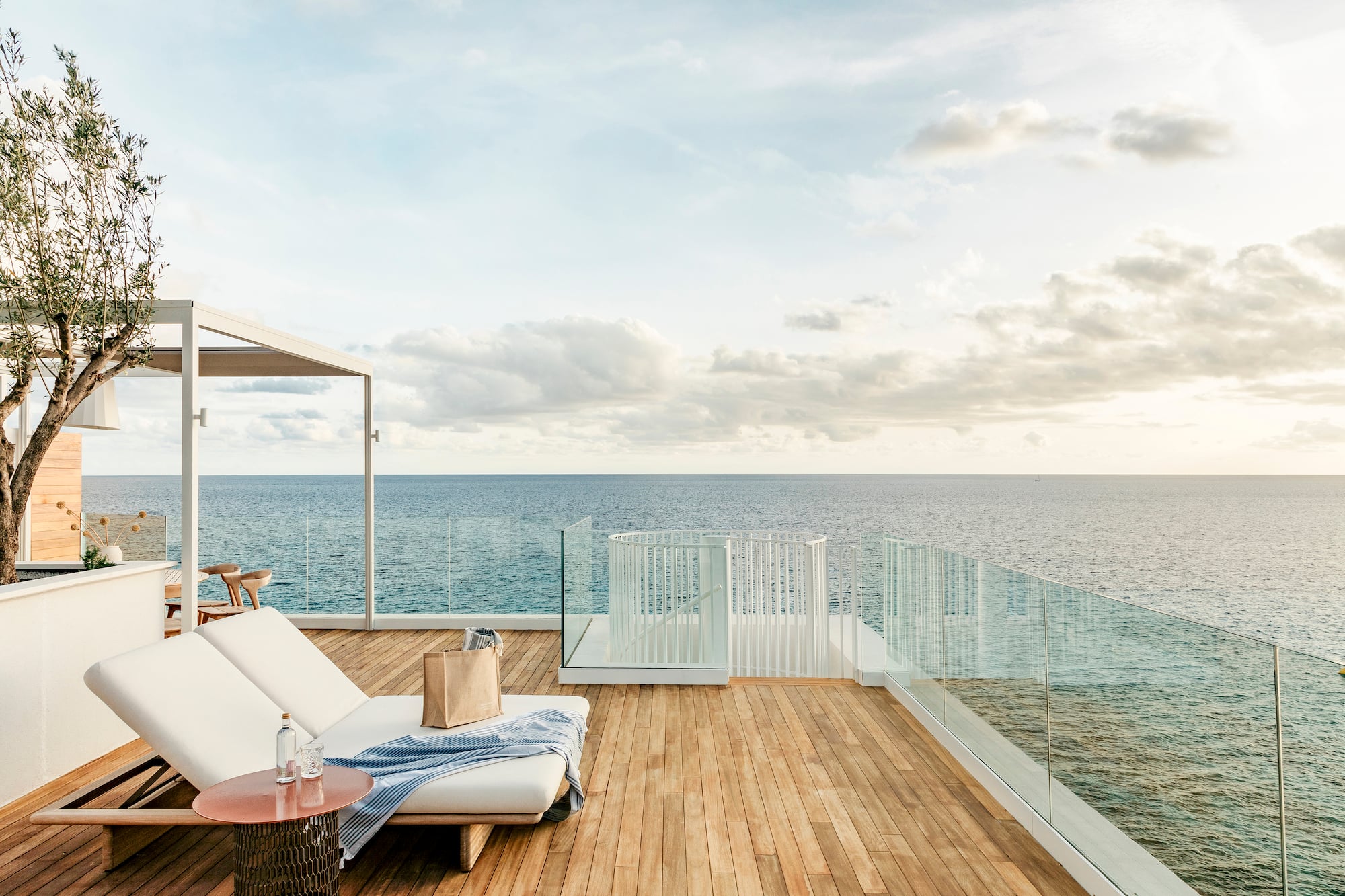 a deck with a chair and table overlooking the ocean