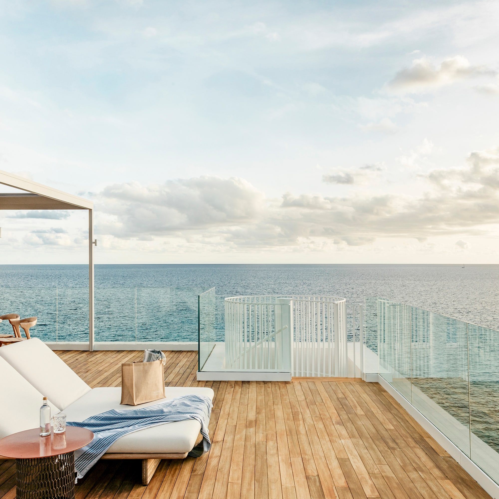a deck with a chair and table overlooking the ocean