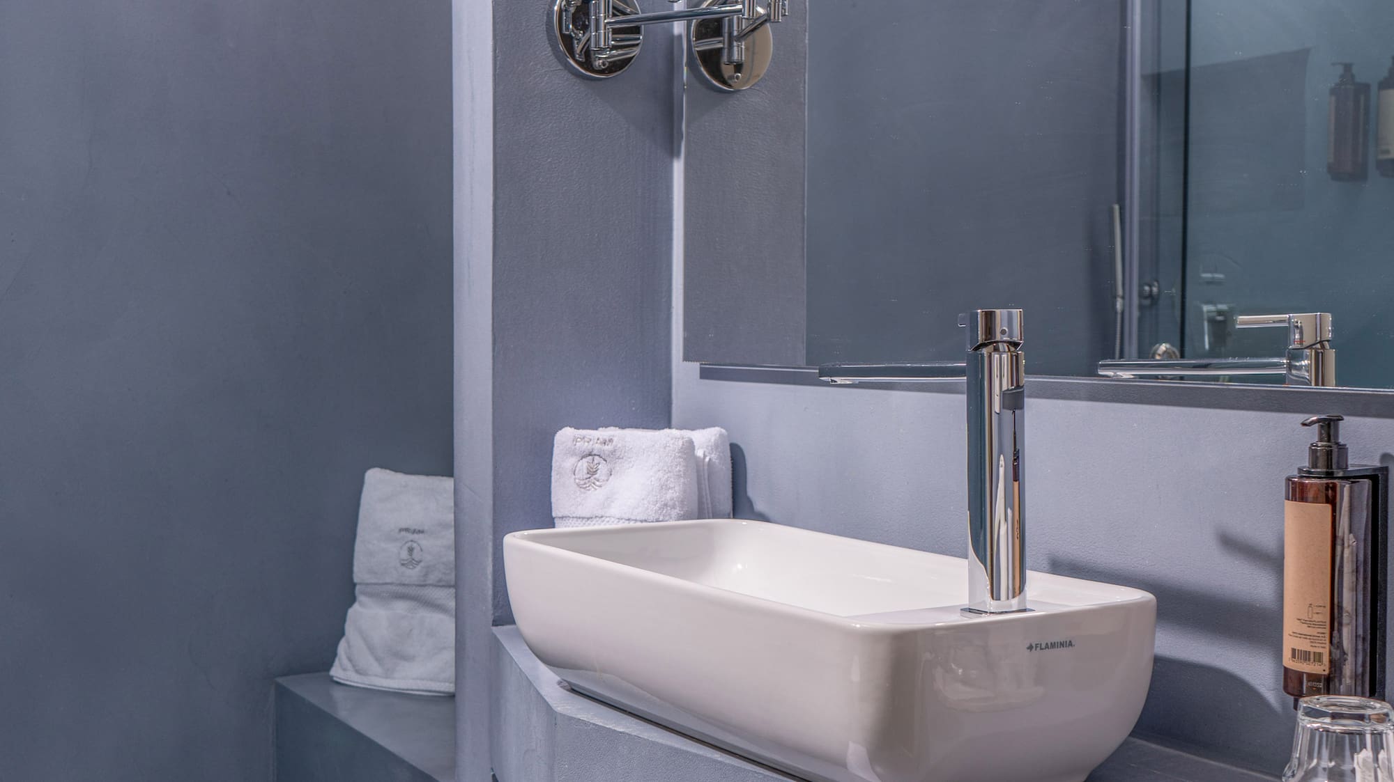 Chic gray bathroom featuring a rectangular sink, mirror, and glass shower.