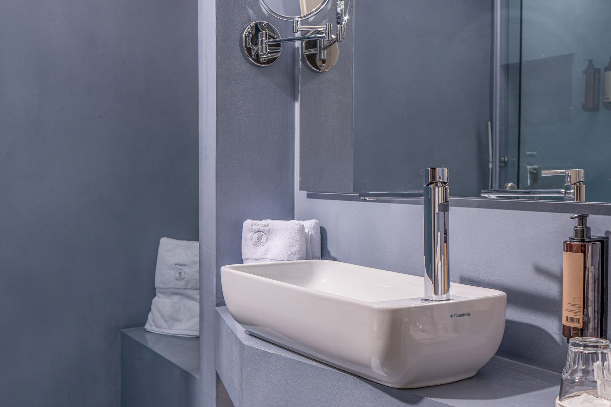 Chic gray bathroom featuring a rectangular sink, mirror, and glass shower.