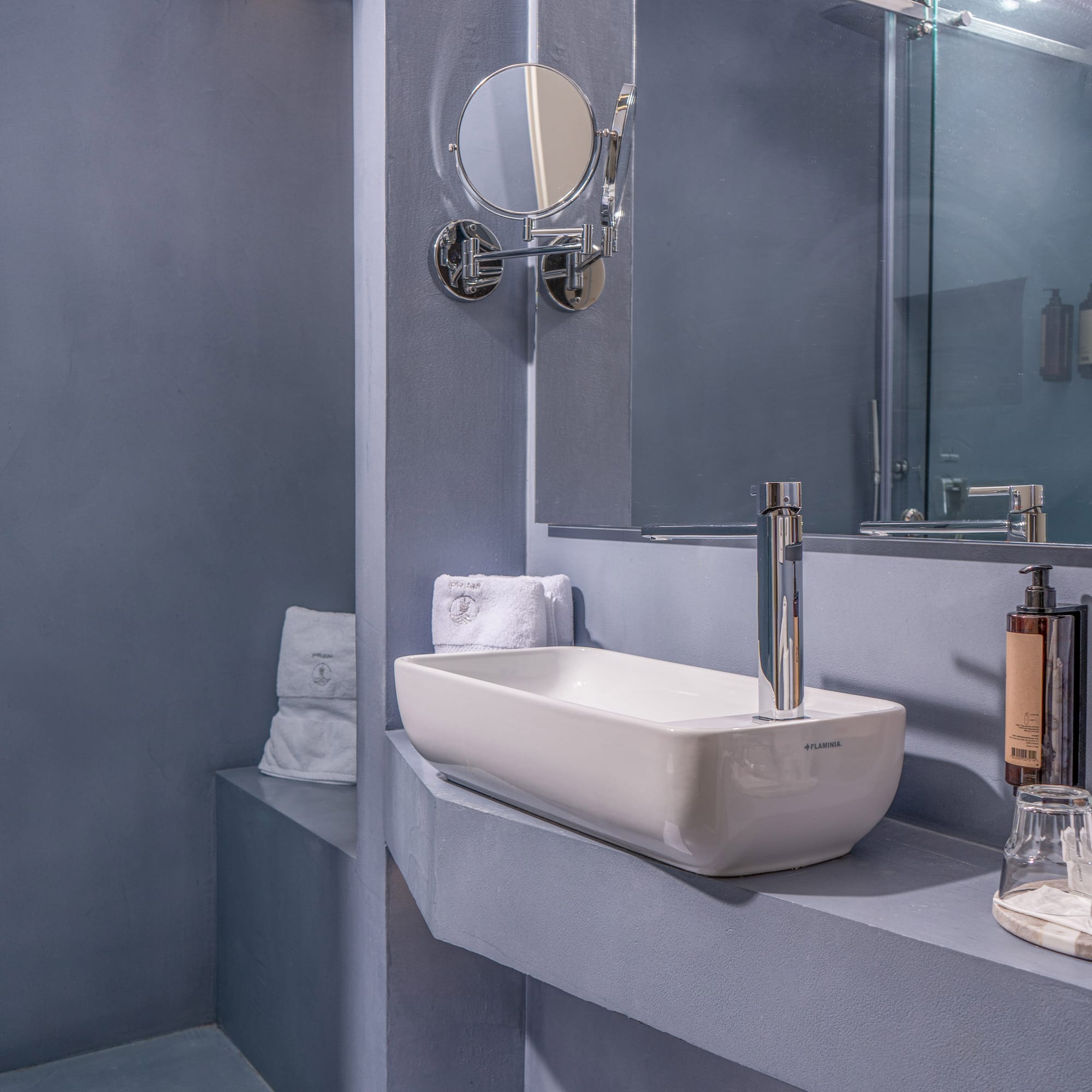Chic gray bathroom featuring a rectangular sink, mirror, and glass shower.