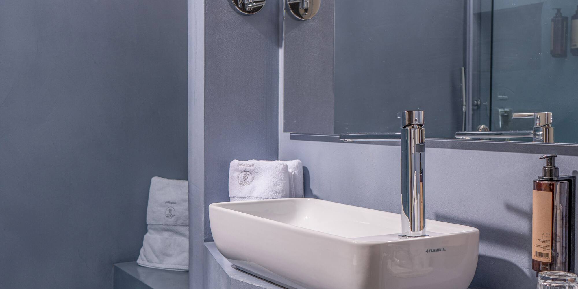 Chic gray bathroom featuring a rectangular sink, mirror, and glass shower.