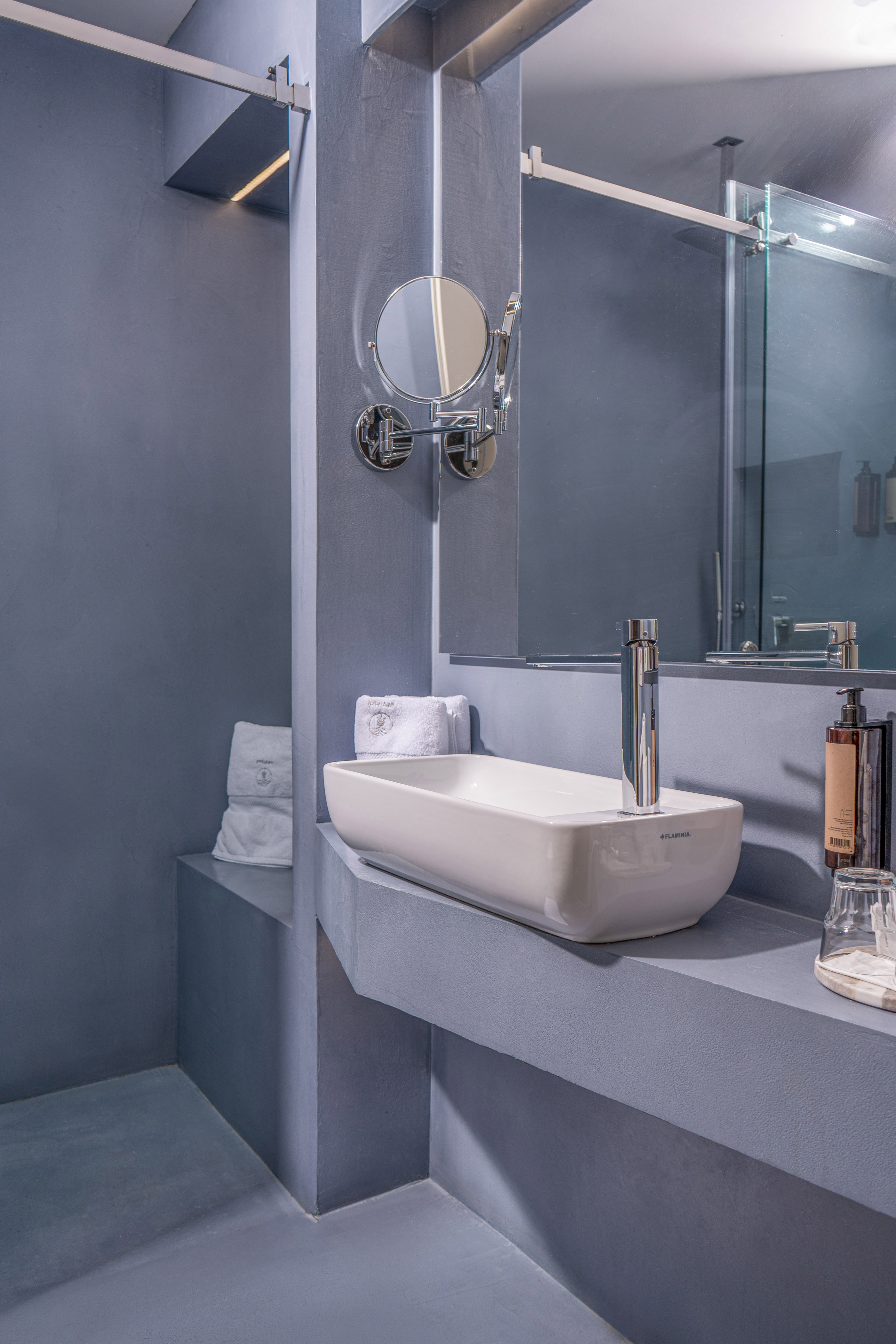 Chic gray bathroom featuring a rectangular sink, mirror, and glass shower.
