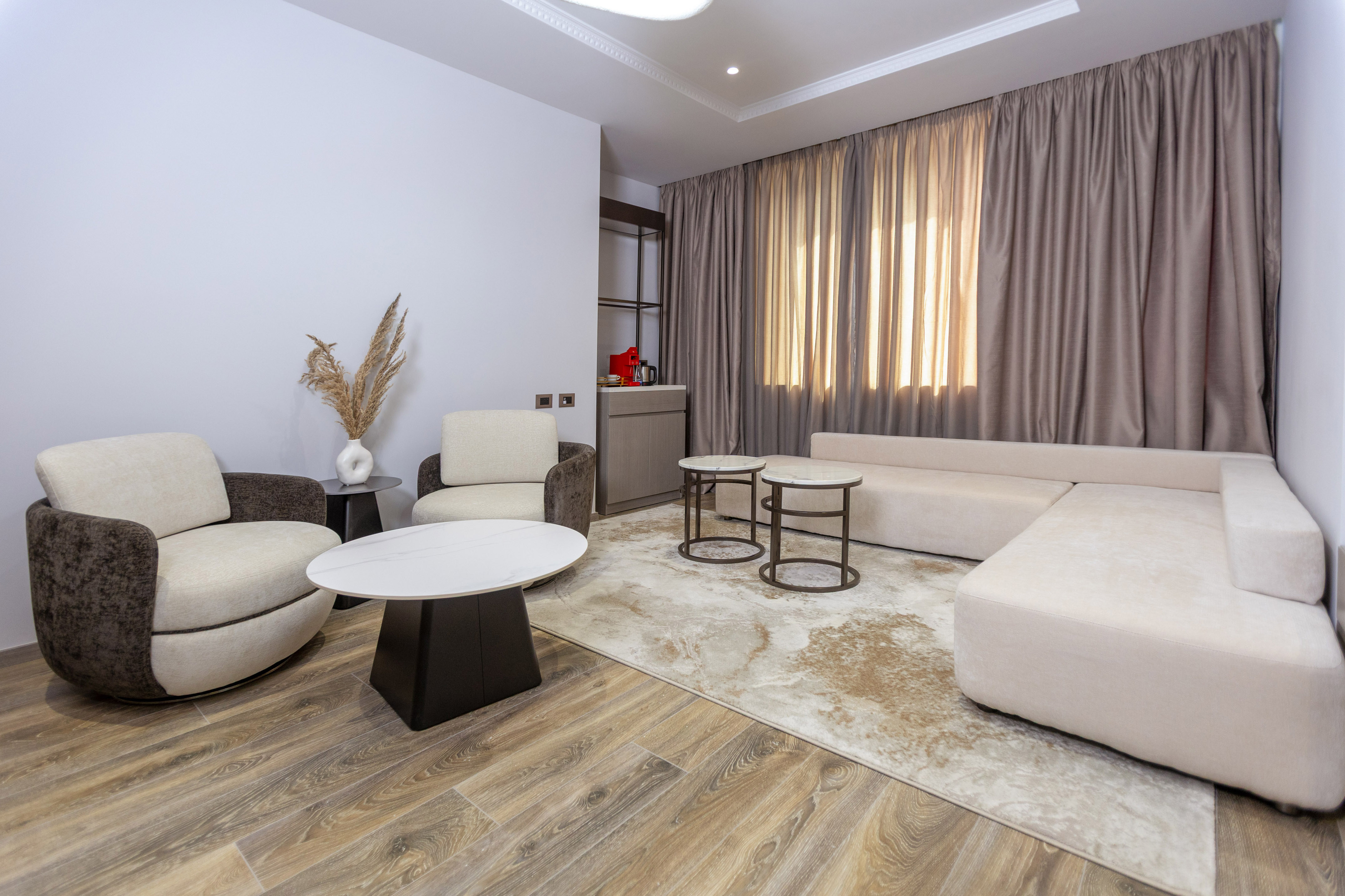 Modern living room with cream sofa, armchairs, coffee table, and wood flooring.