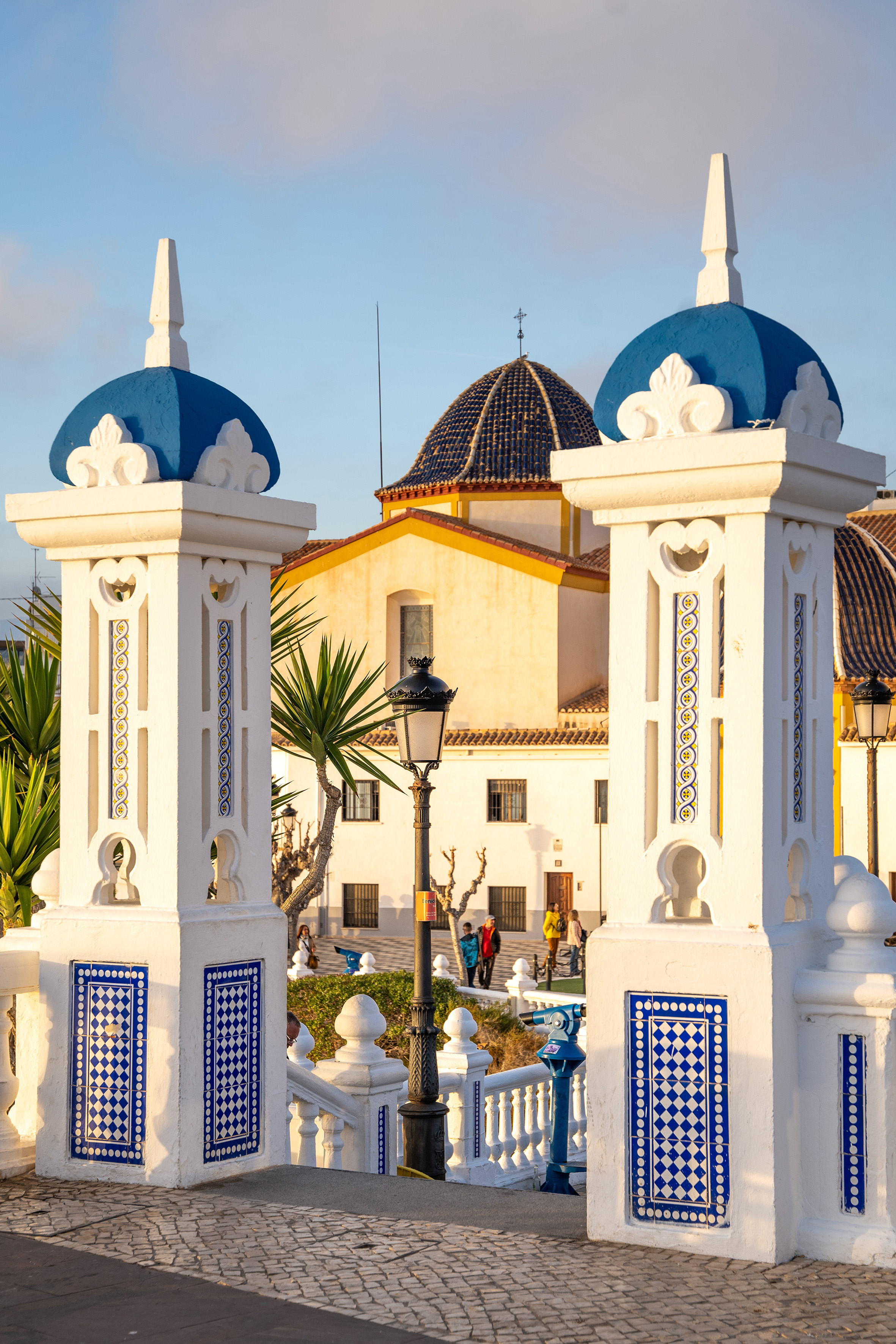 White pillars with blue tiled domes framing Benidorm's iconic church and plaza.