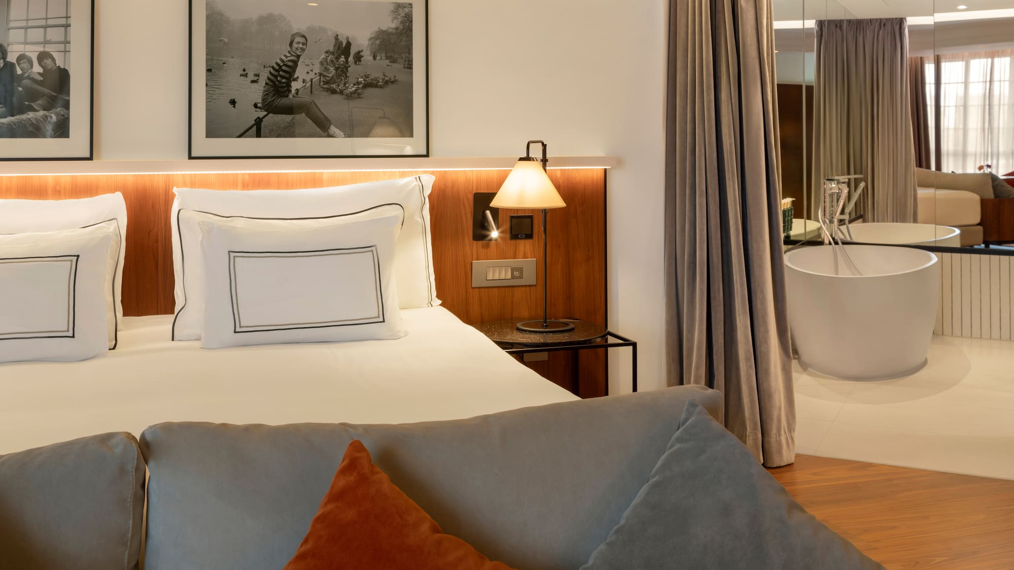 Modern hotel room with king bed, sofa, and freestanding bathtub.