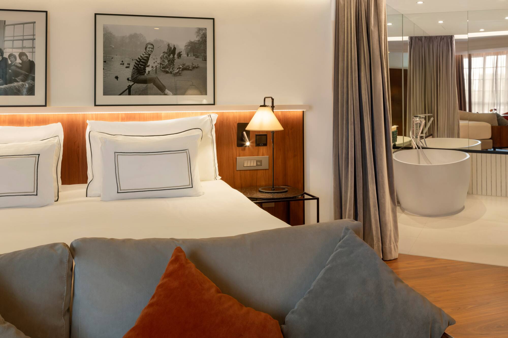 Modern hotel room with king bed, sofa, and freestanding bathtub.