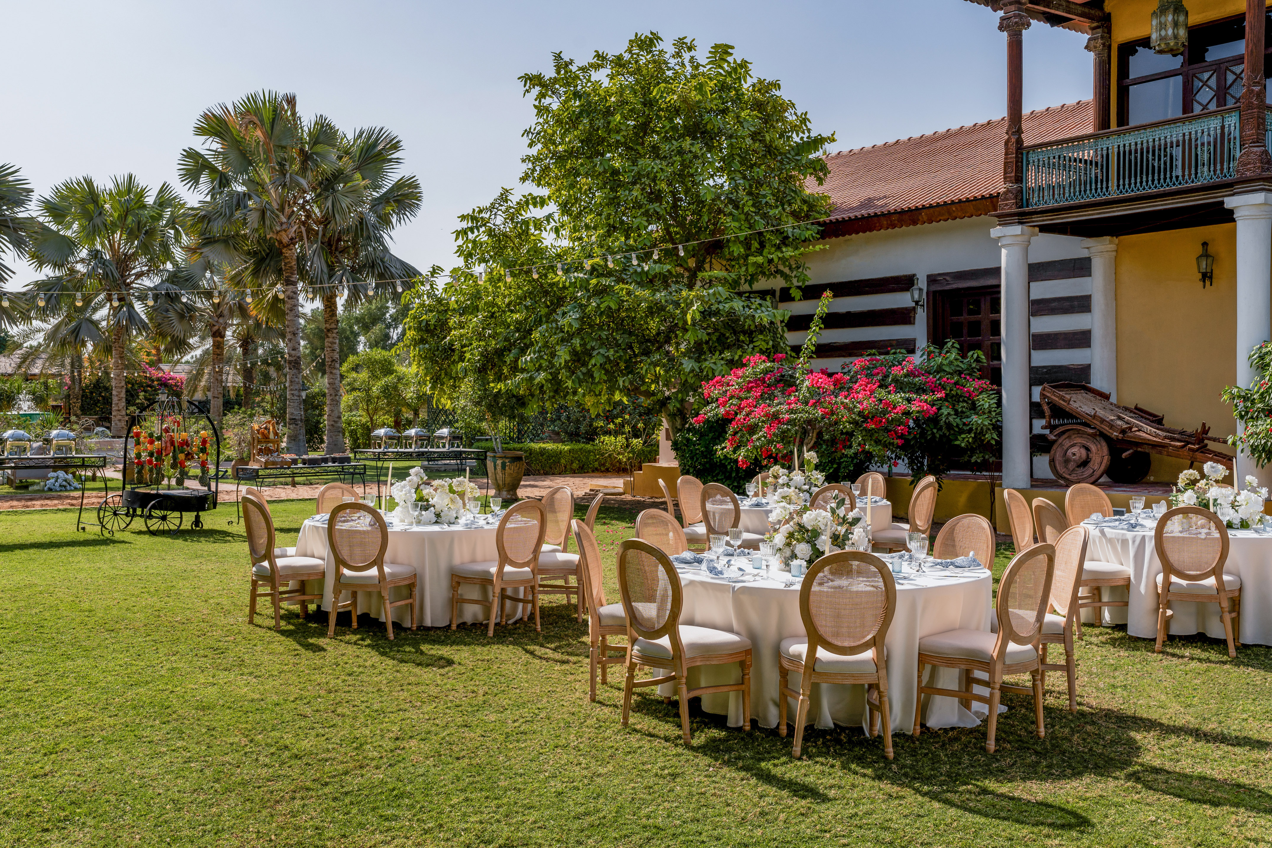 Outdoor dining tables, green lawn, white floral decor, resort villa.