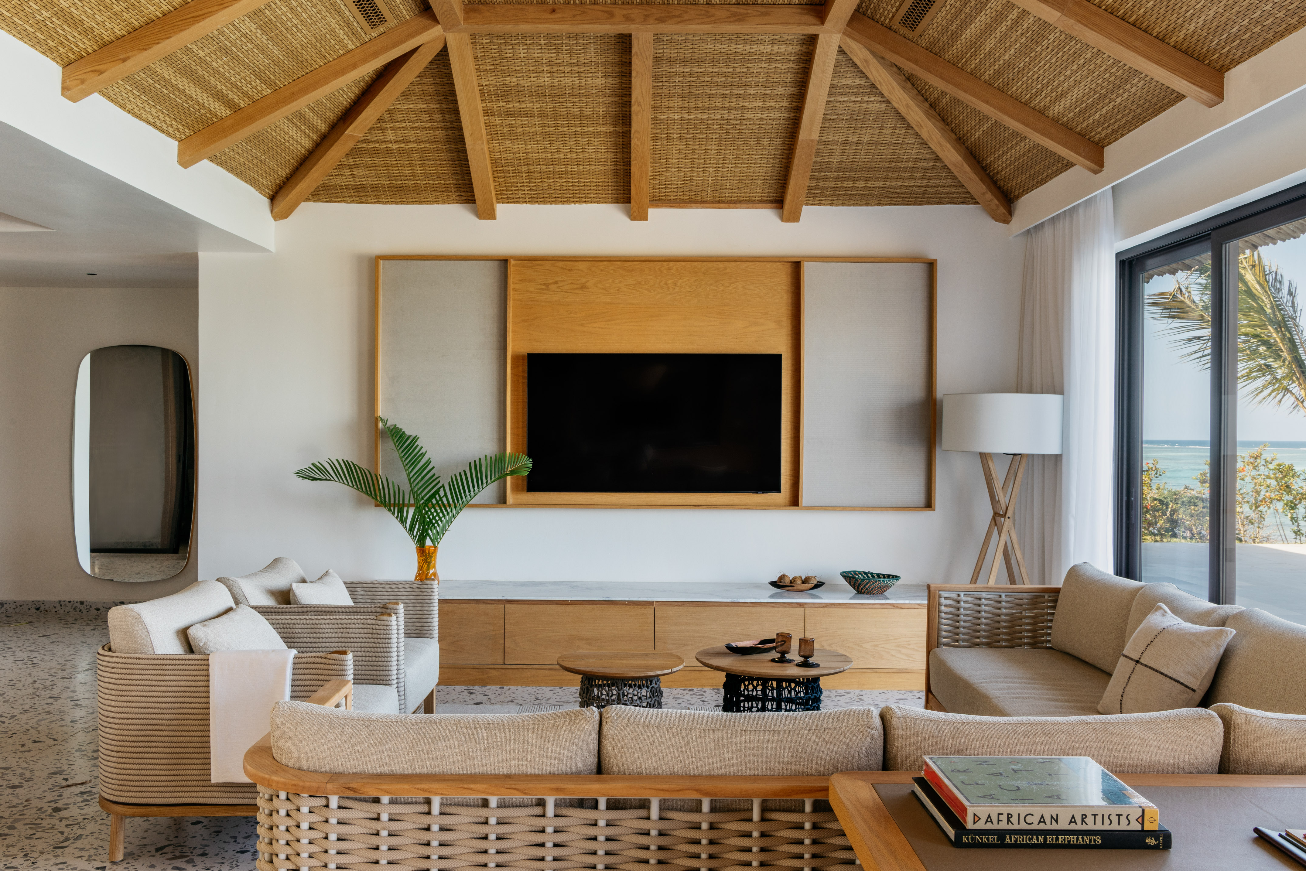 Modern tropical living room with vaulted rattan ceiling, ocean view, natural textures.