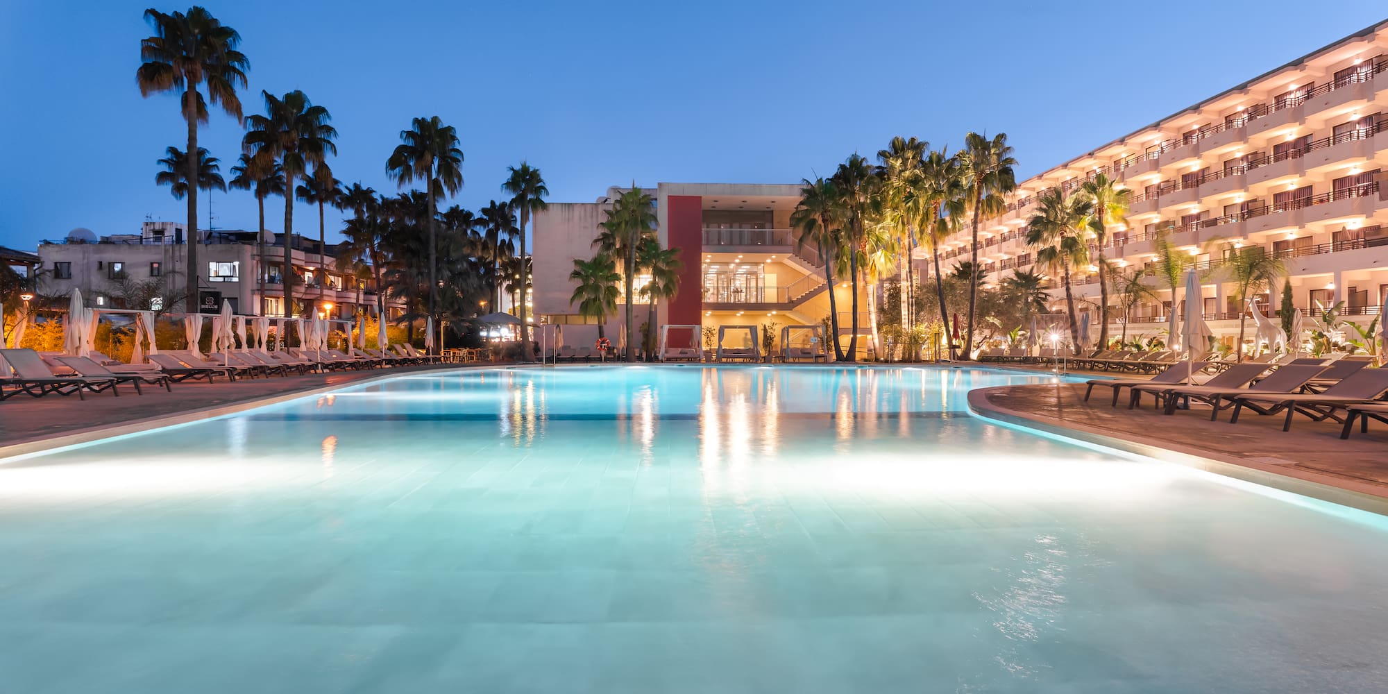 a pool with palm trees and buildings