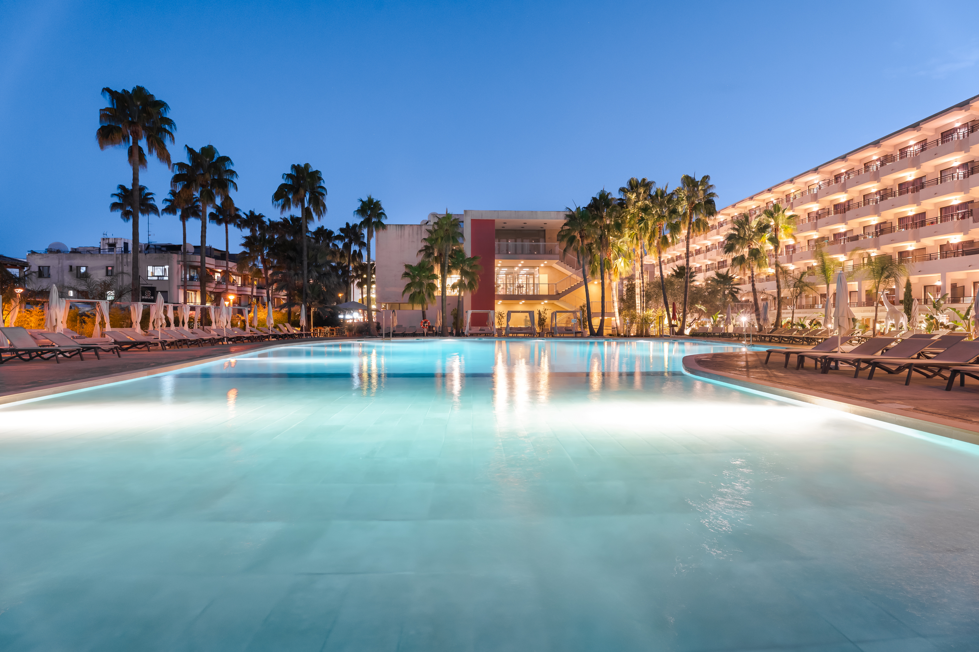 a pool with palm trees and buildings