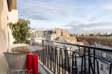 a table and chair on a balcony with a view of a city