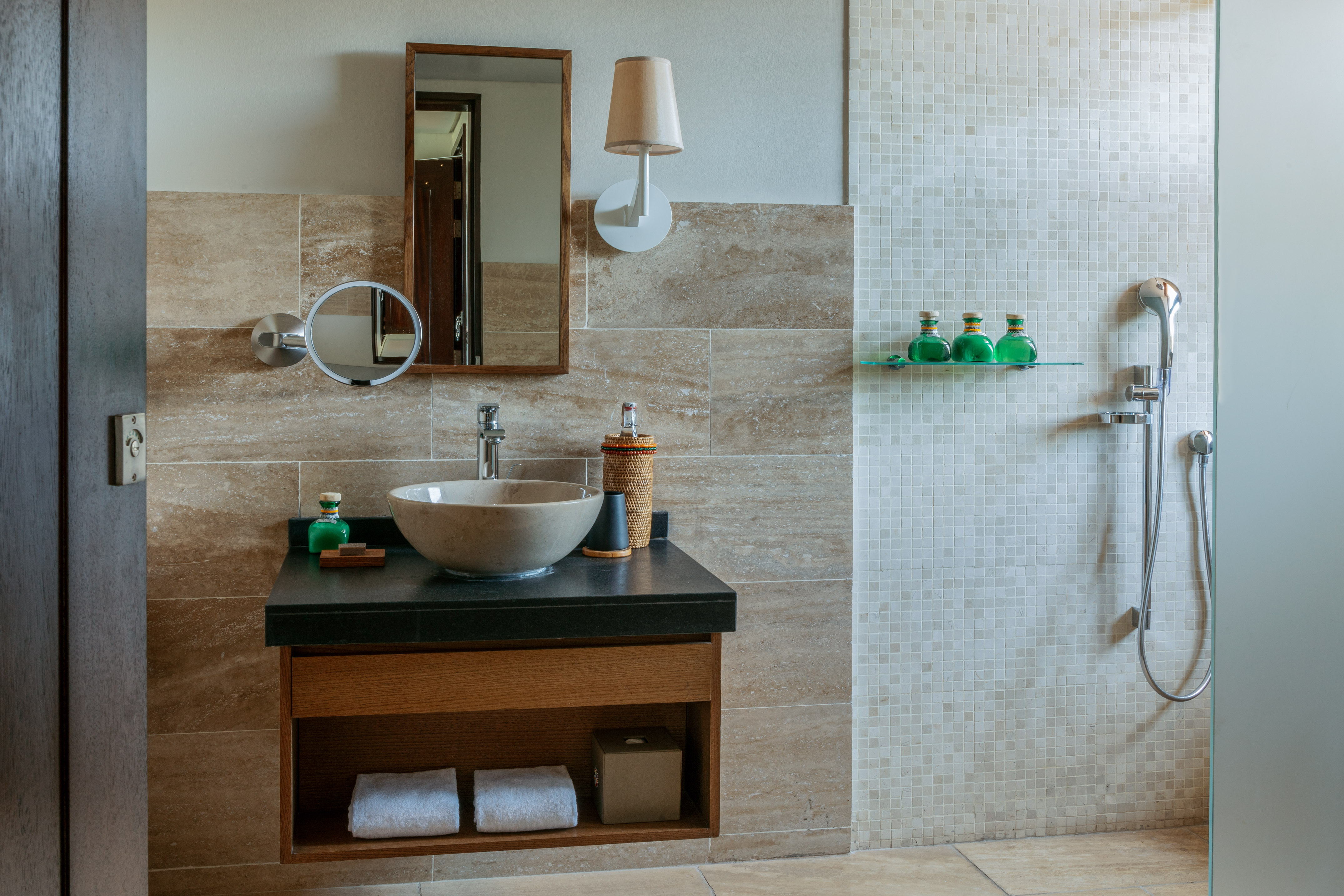 Modern bathroom with vessel sink, wooden vanity, mirror, and mosaic shower.