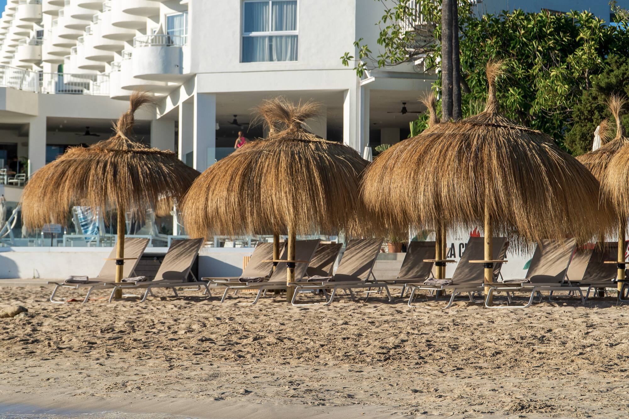 Sandy beach, thatched umbrellas, sun loungers, and hotel resort.