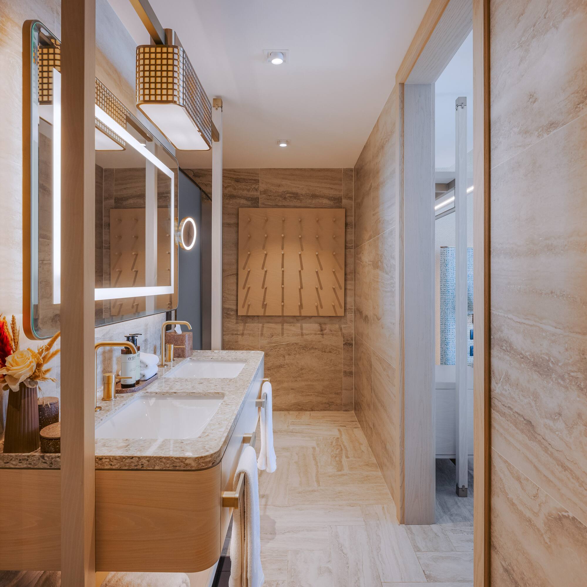 Luxury double vanity bathroom with illuminated mirrors and stone walls.