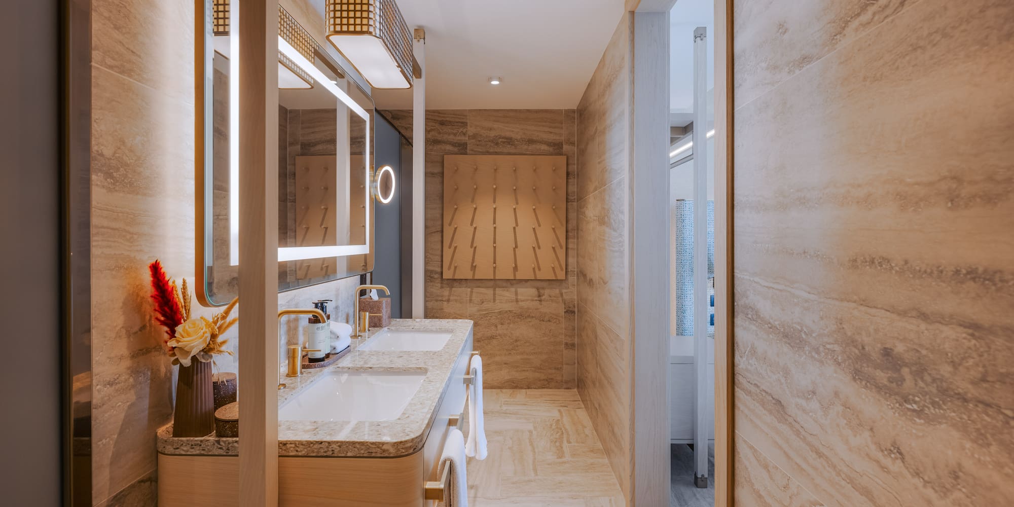 Luxury double vanity bathroom with illuminated mirrors and stone walls.