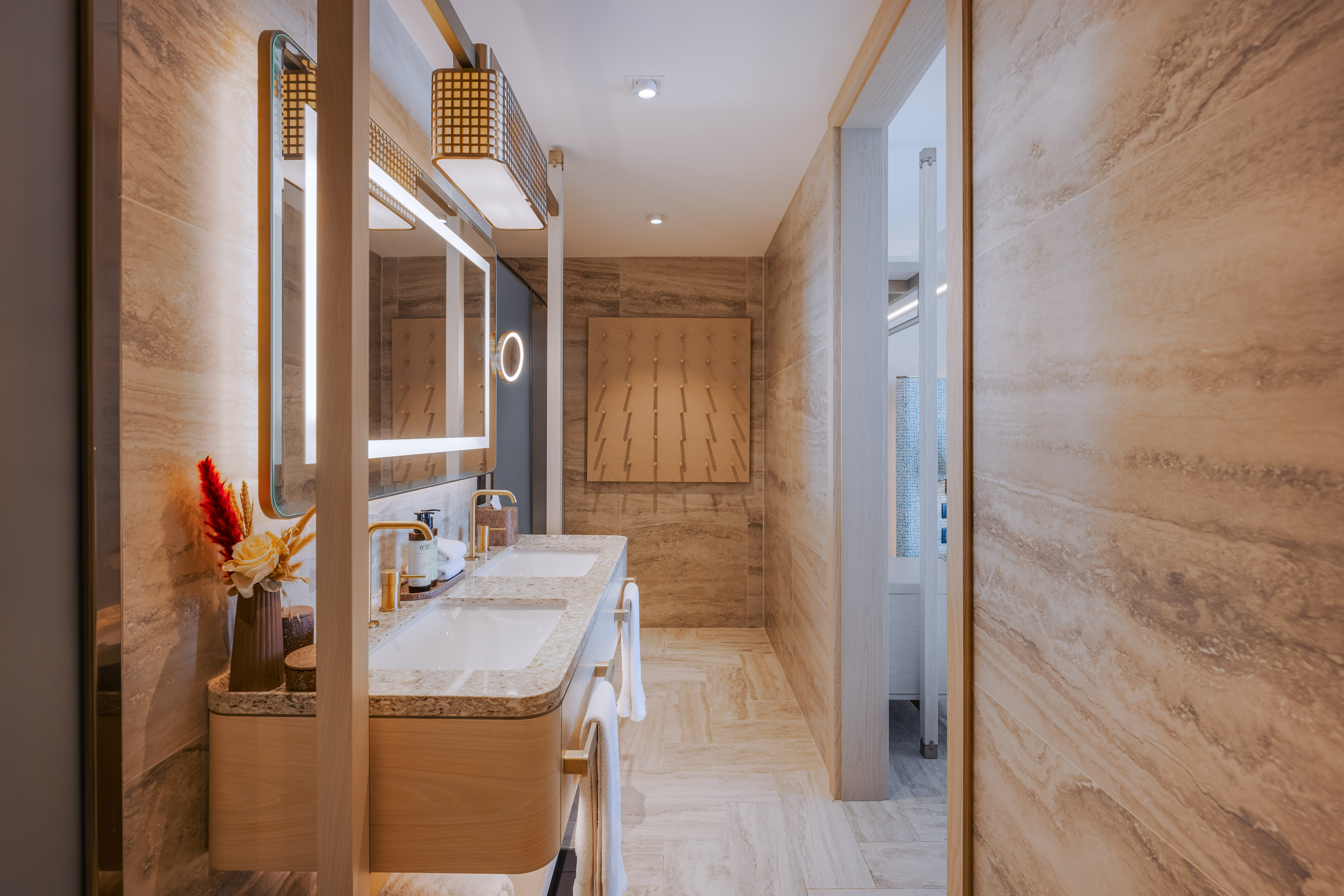Luxury double vanity bathroom with illuminated mirrors and stone walls.