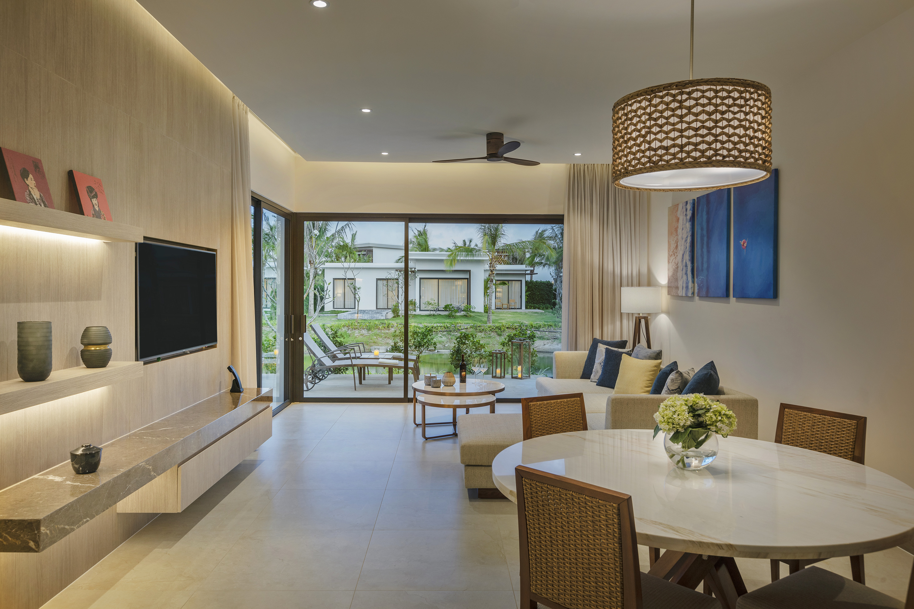 Modern living room with dining area, tropical villa view, and sleek interior design.