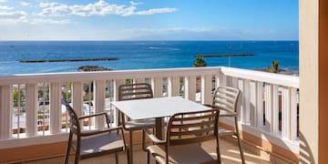 a table and chairs on a balcony overlooking the ocean