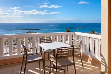 a table and chairs on a balcony overlooking the ocean