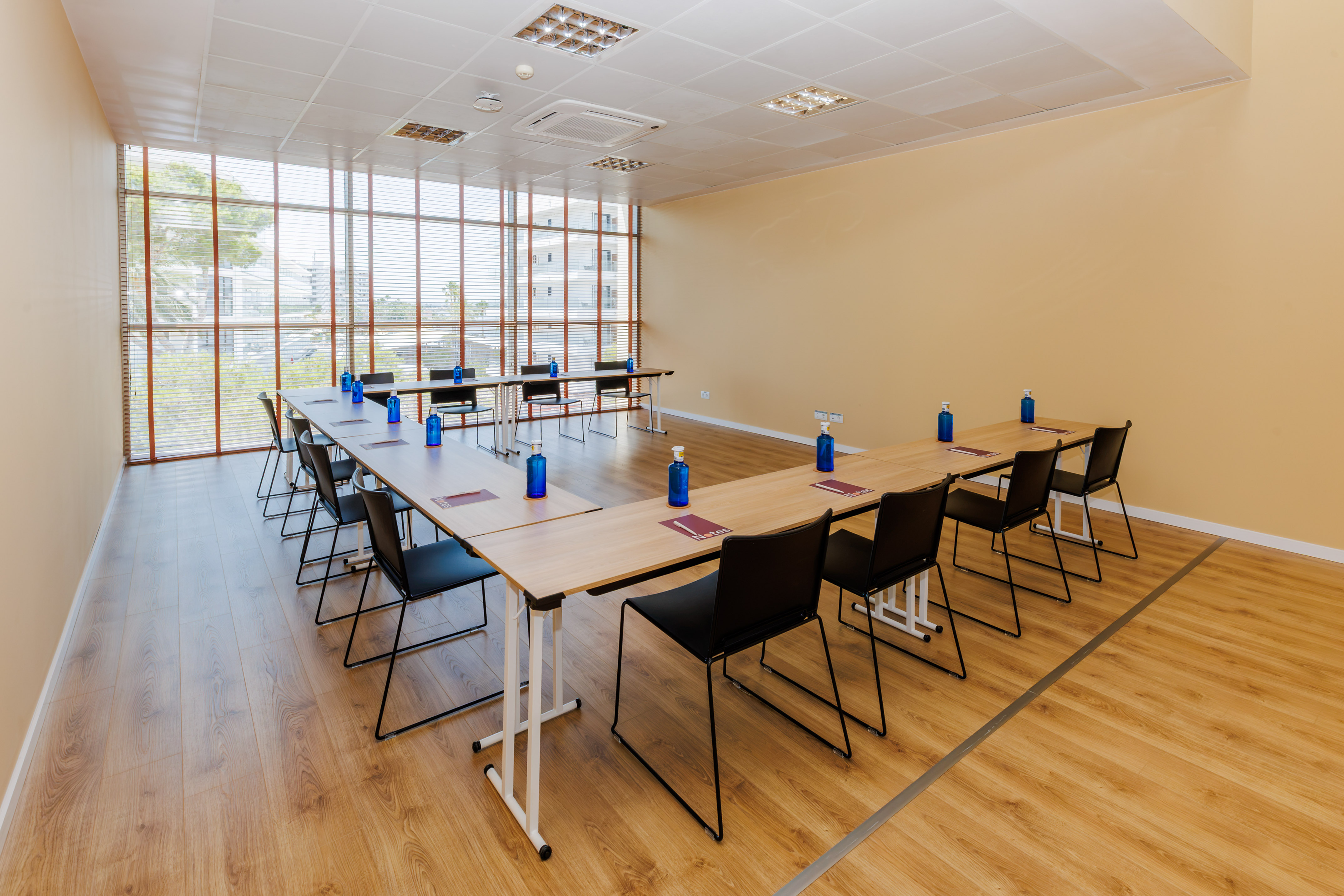 U-shaped conference room with black chairs, wooden floor, and large windows.