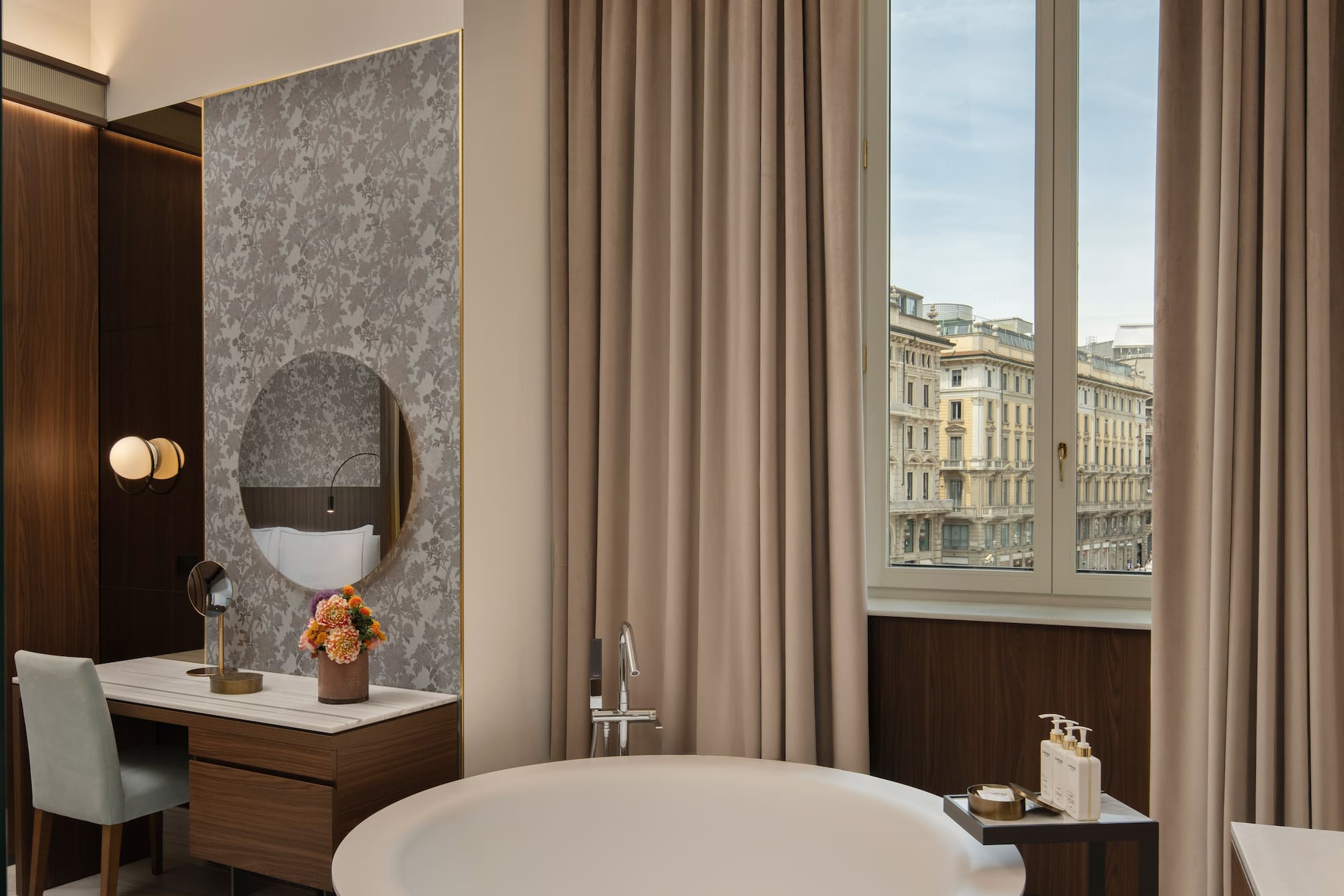 Luxury hotel suite with city view, freestanding bathtub, and elegant vanity.