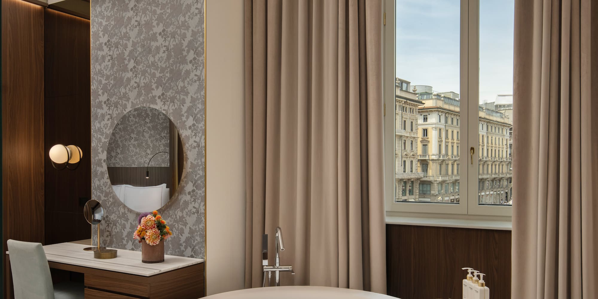 Luxury hotel suite with city view, freestanding bathtub, and elegant vanity.