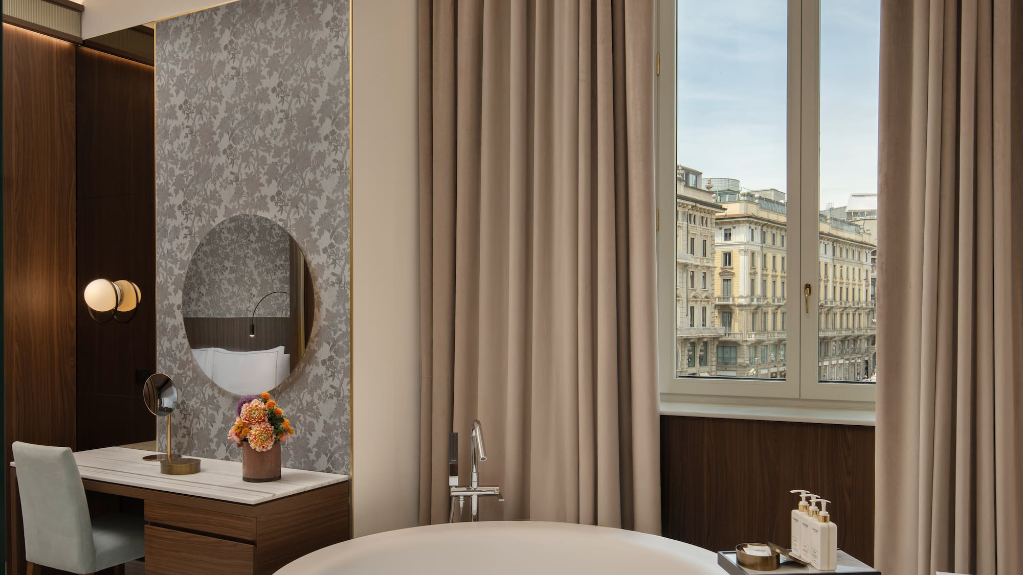 Luxury hotel suite with city view, freestanding bathtub, and elegant vanity.
