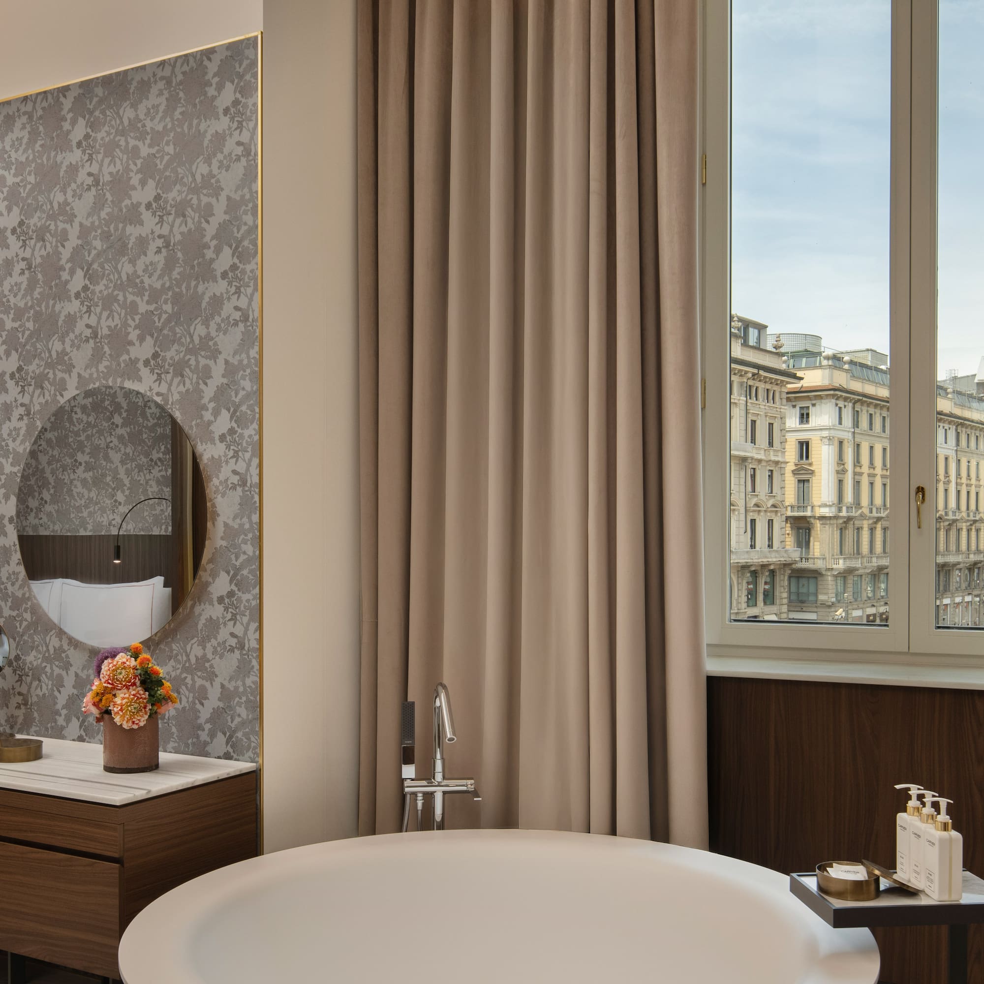 Luxury hotel suite with city view, freestanding bathtub, and elegant vanity.