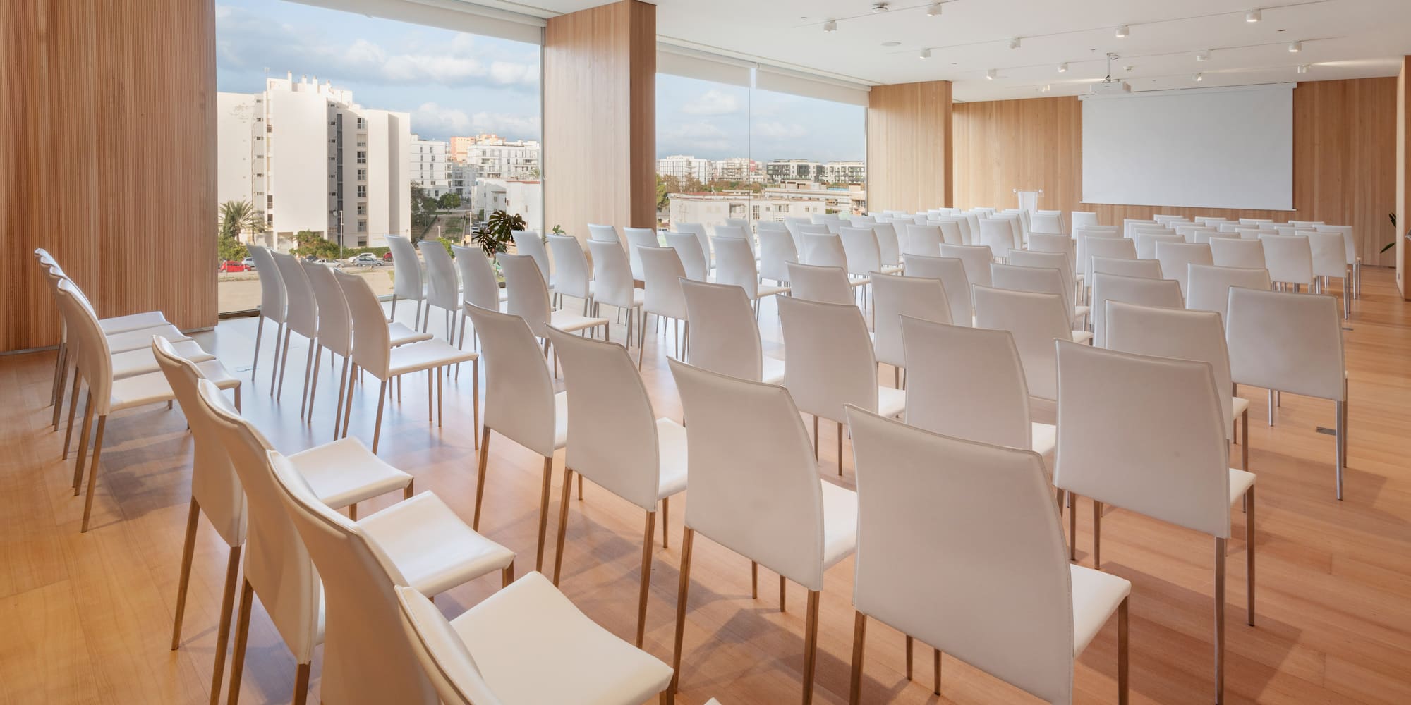 a room with white chairs and a large window