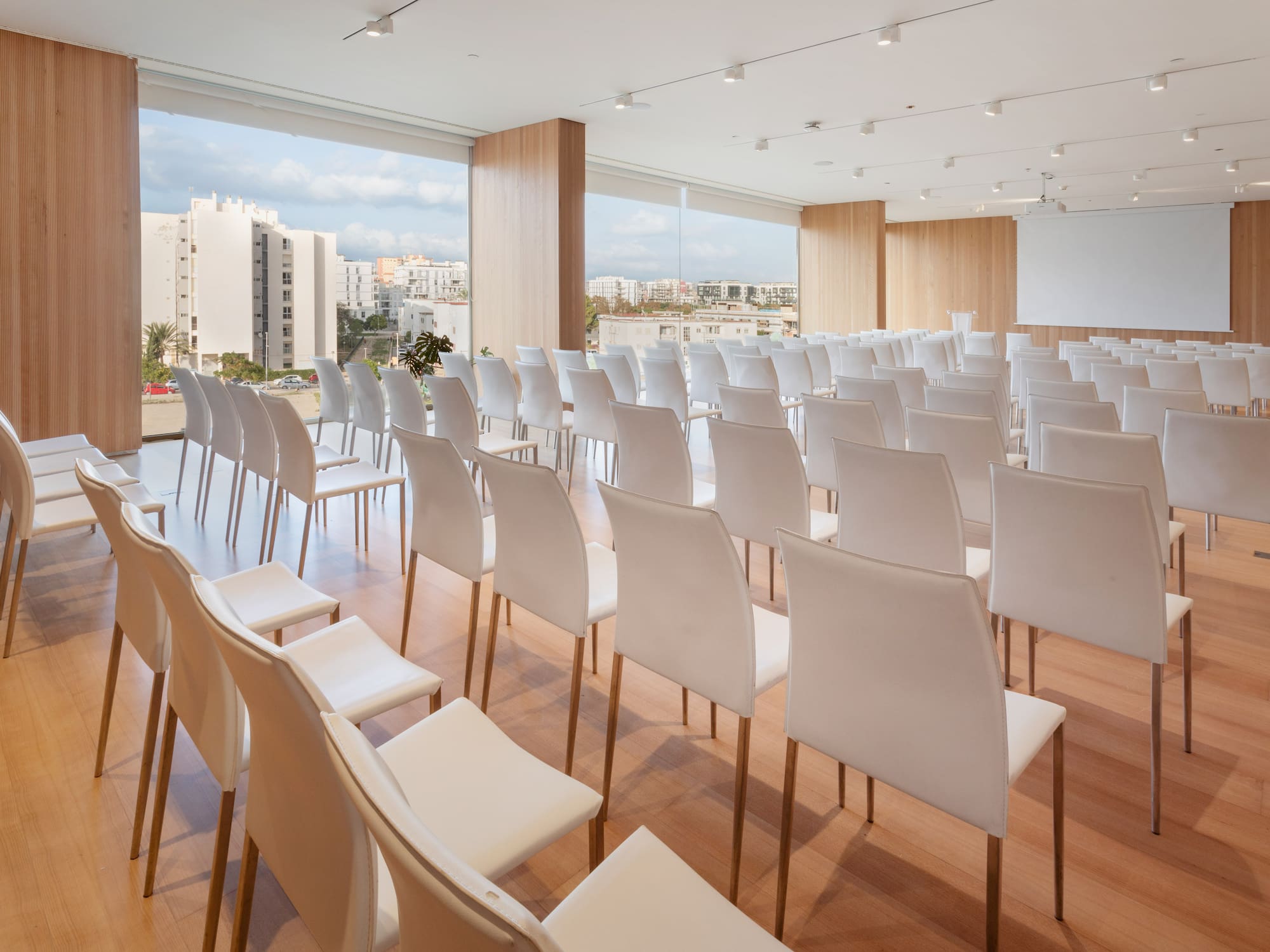 a room with white chairs and a large window