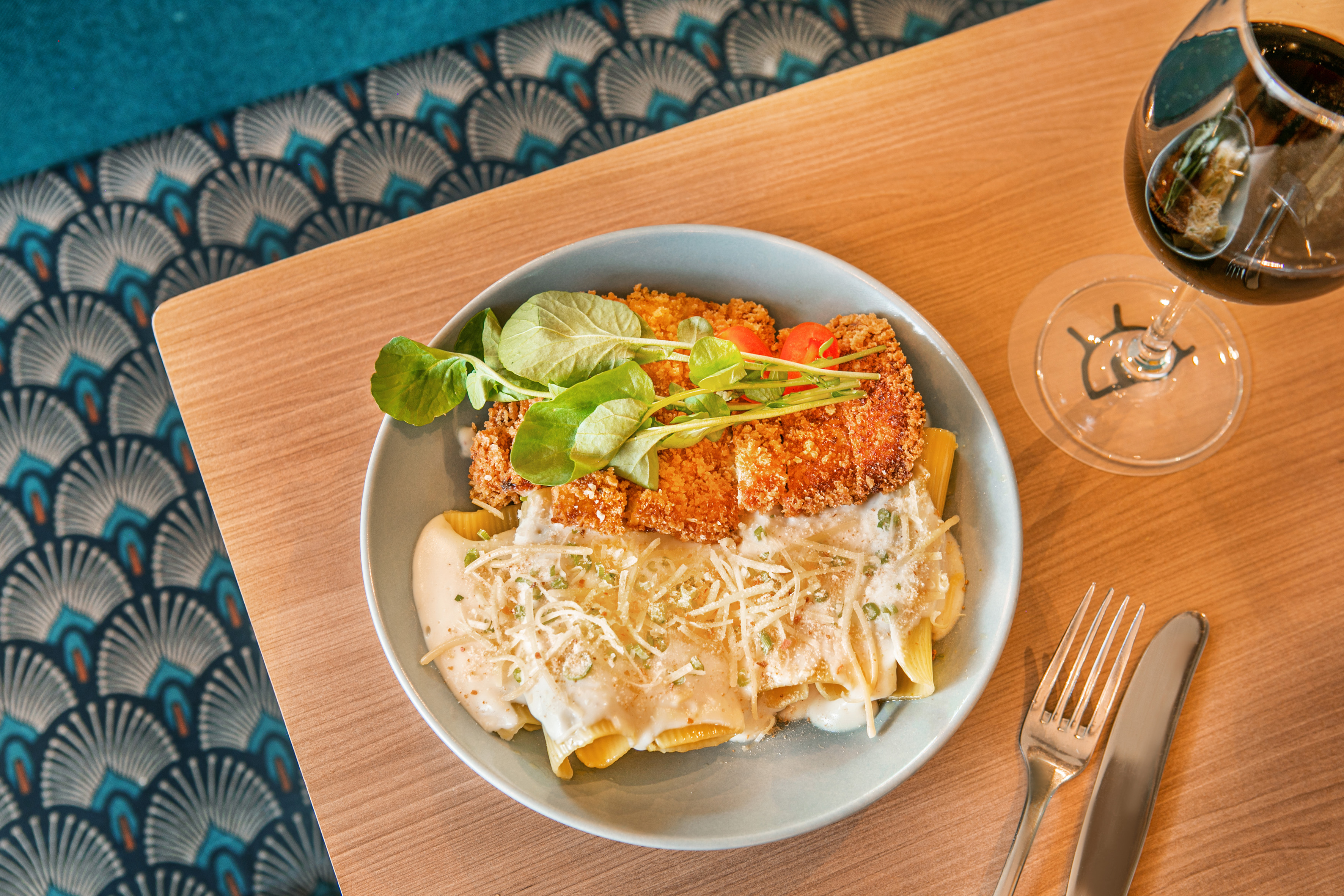 Chicken katsu with creamy pasta, greens, grated cheese, and red wine.