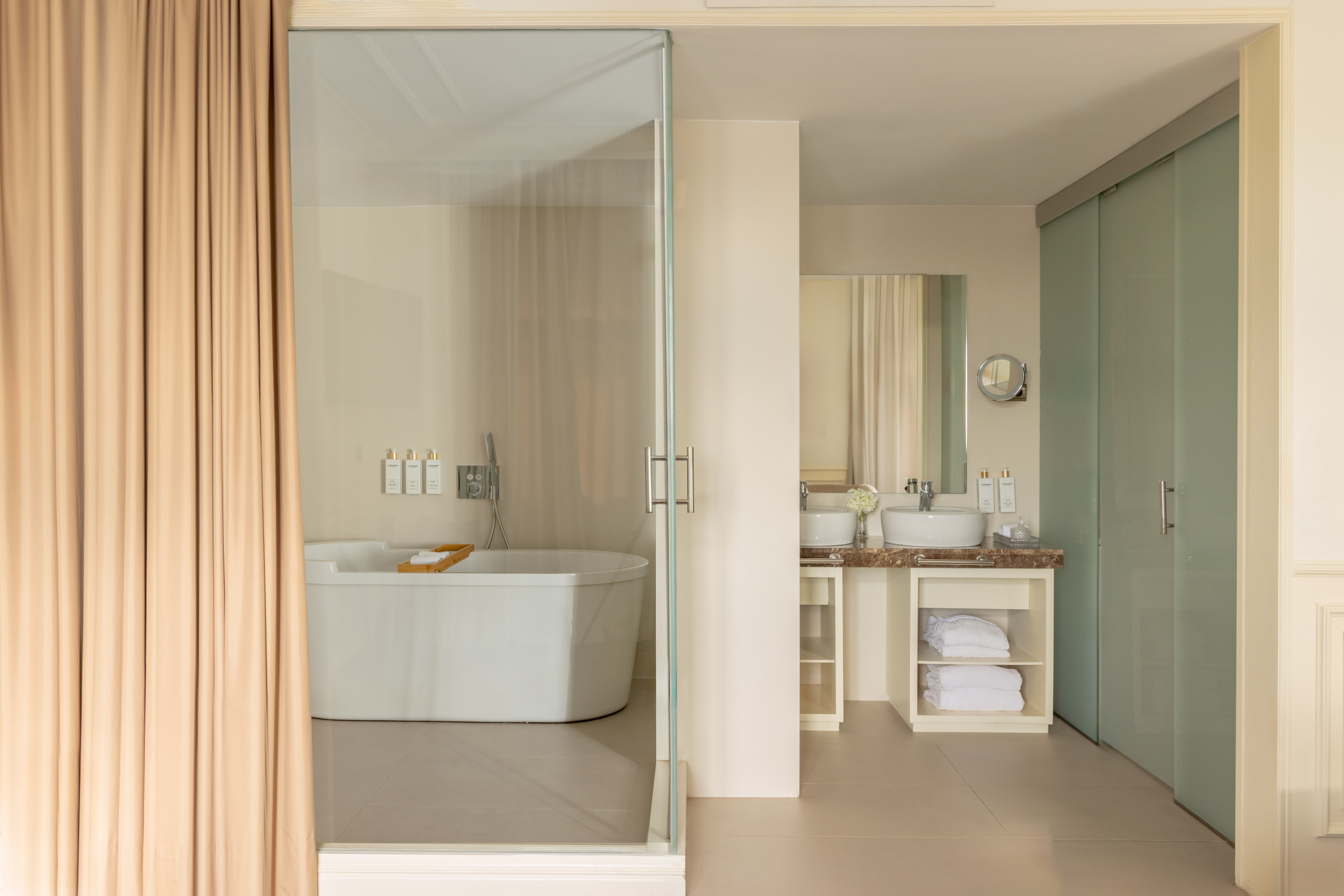 Bright luxury bathroom with freestanding tub, glass partition, double vanity.