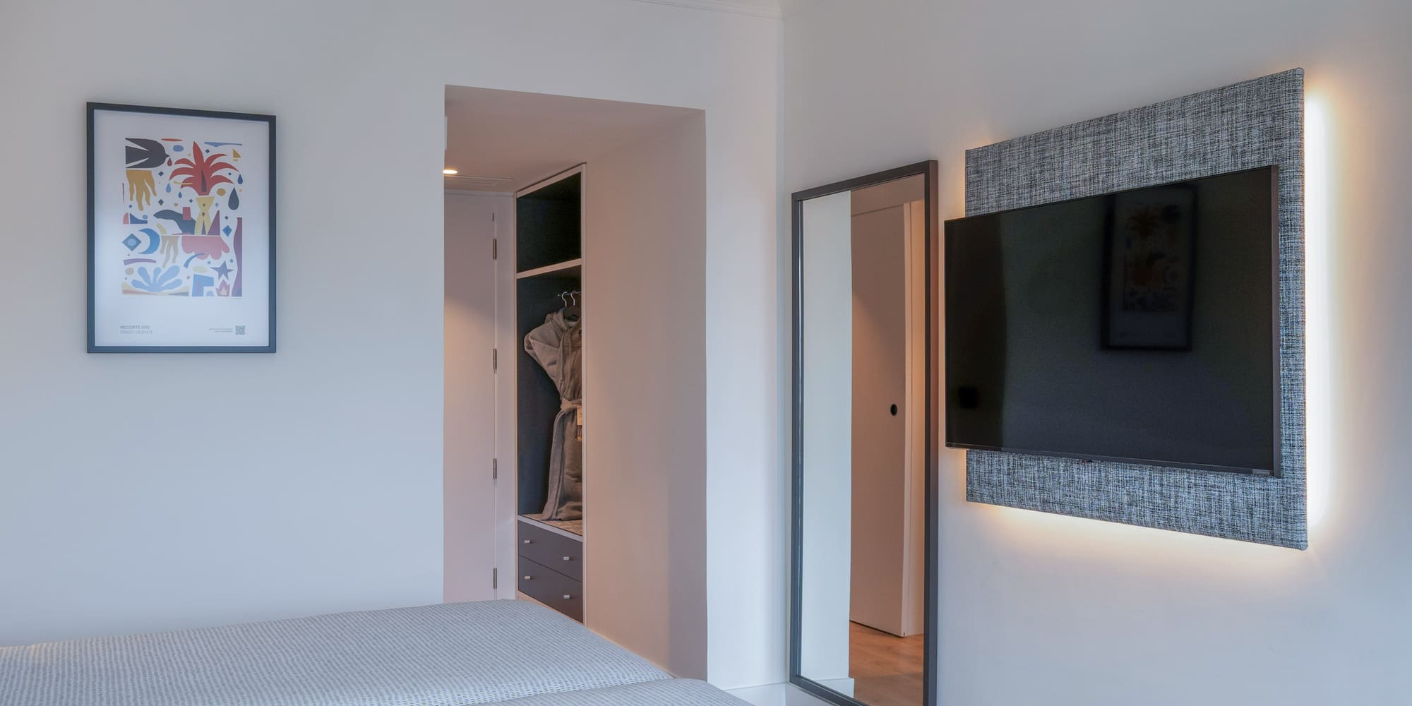 Dormitorio de hotel moderno con camas, TV retroiluminada, espejo y armario.