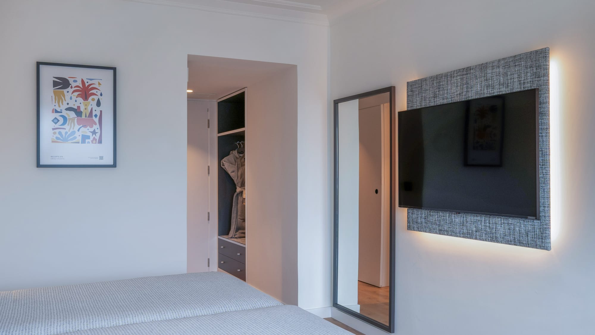Dormitorio de hotel moderno con camas, TV retroiluminada, espejo y armario.
