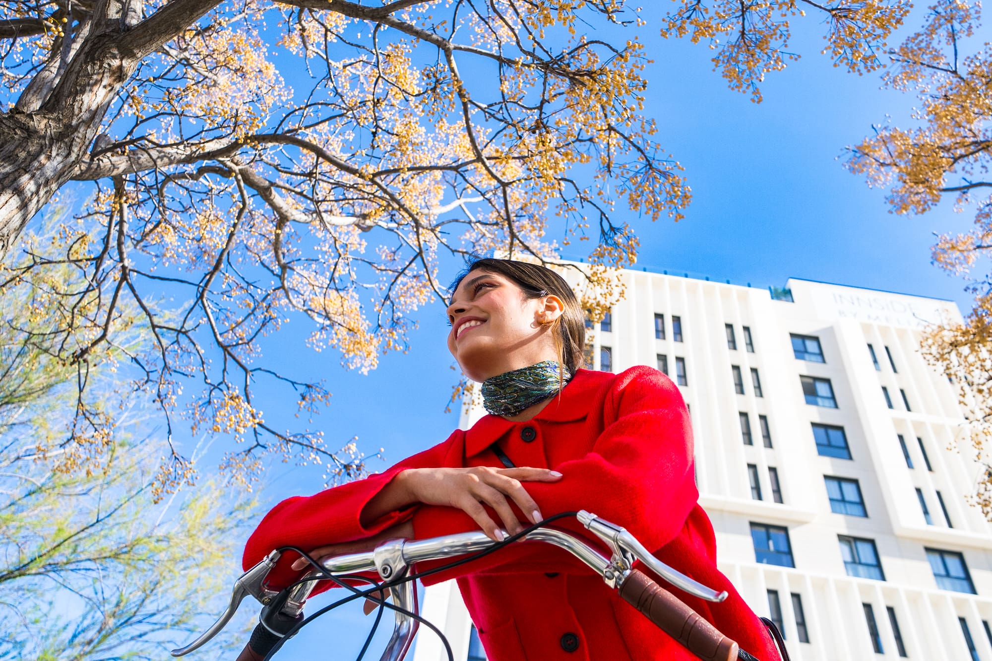 a woman in a red coat on a bicycle