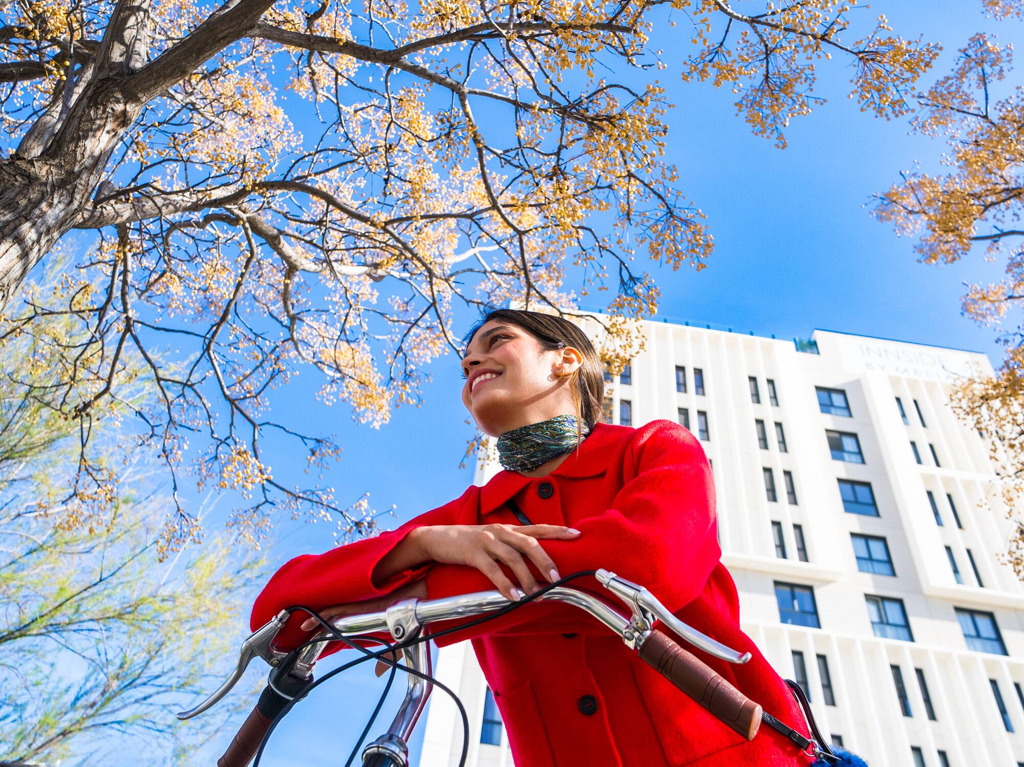 a woman in a red coat on a bicycle