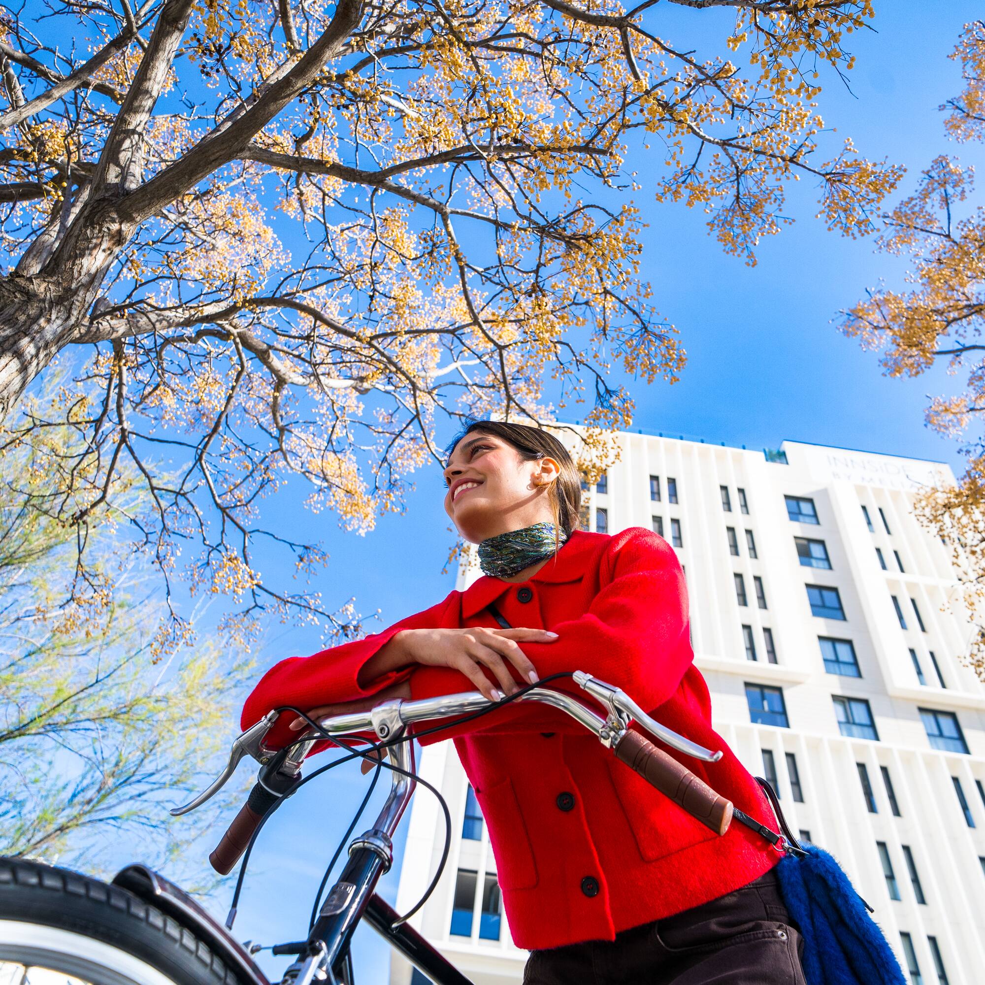 a woman in a red coat on a bicycle