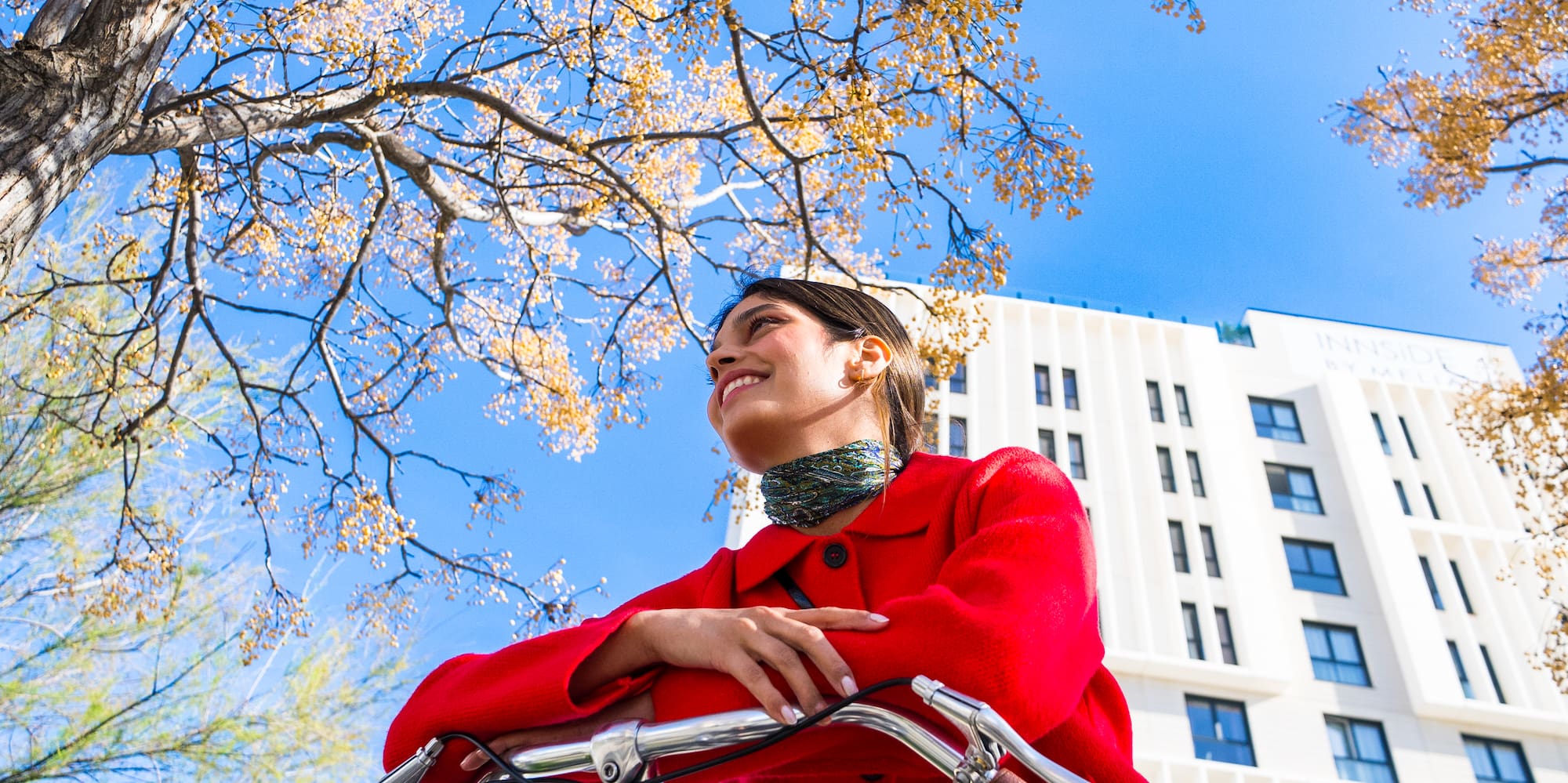 a woman in a red coat on a bicycle