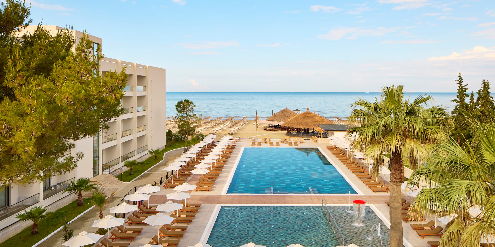 a swimming pool with umbrellas and chairs by a building