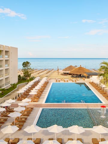 a swimming pool with umbrellas and chairs by a building