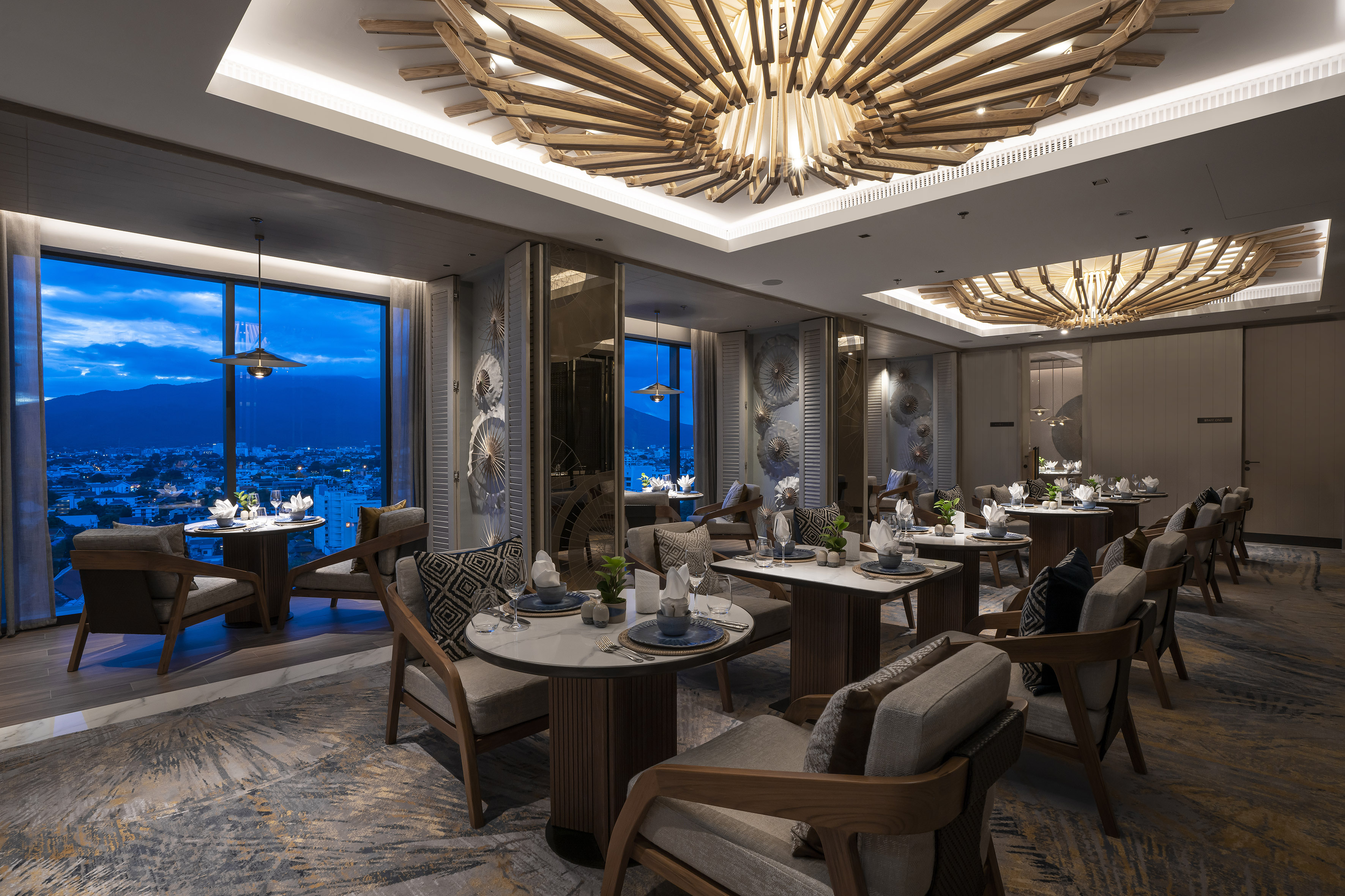 Modern restaurant with unique wooden ceiling, set tables, and panoramic night view.