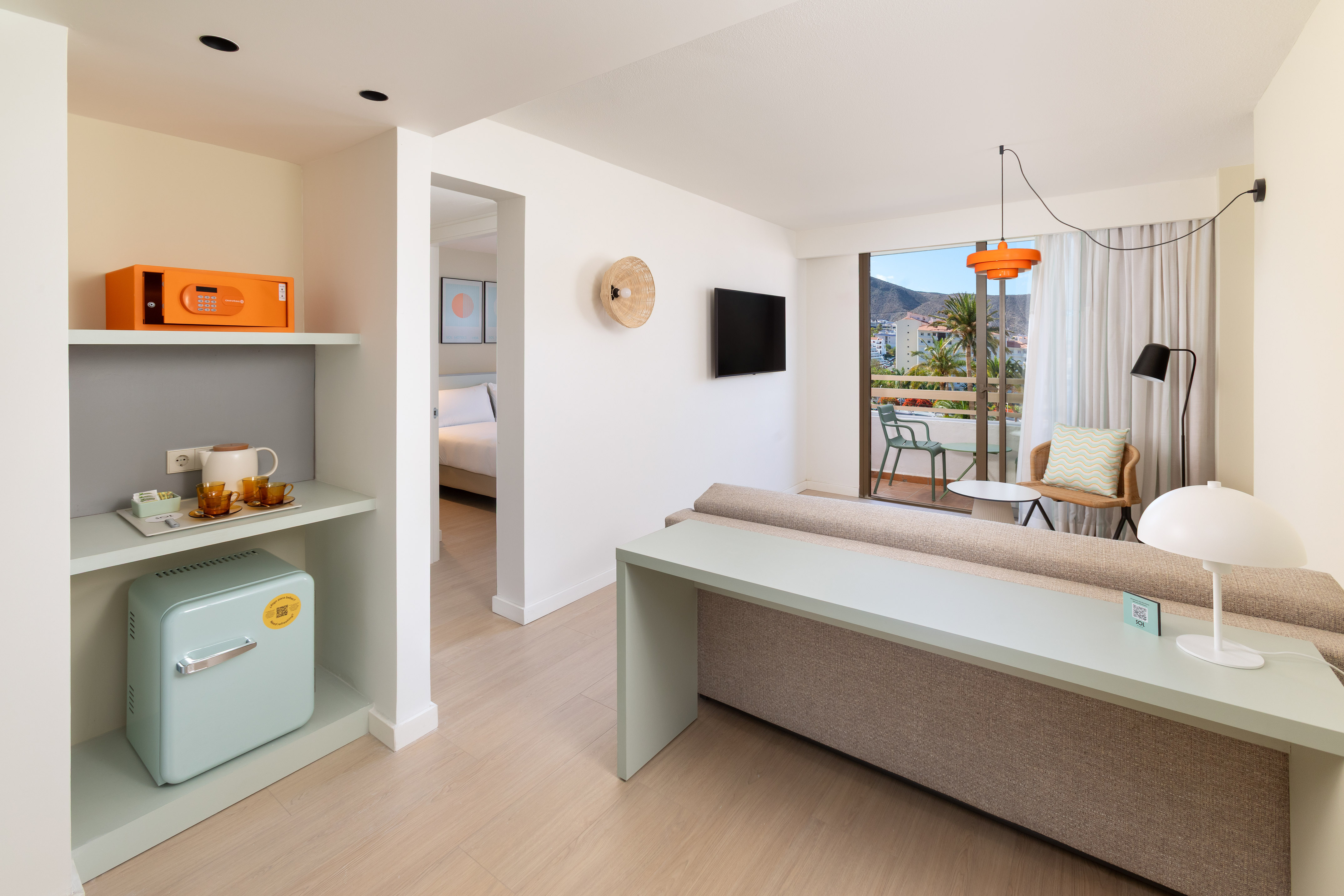 Modern hotel suite with balcony mountain view, living area, bedroom, and mini-bar.